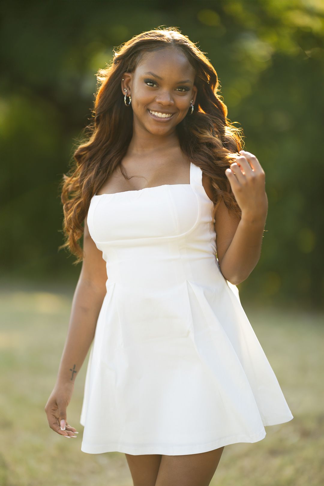 Beautiful summer portrait of someone in a white sundress with flowing hair backlit by golden sunlight in an outdoor setting.