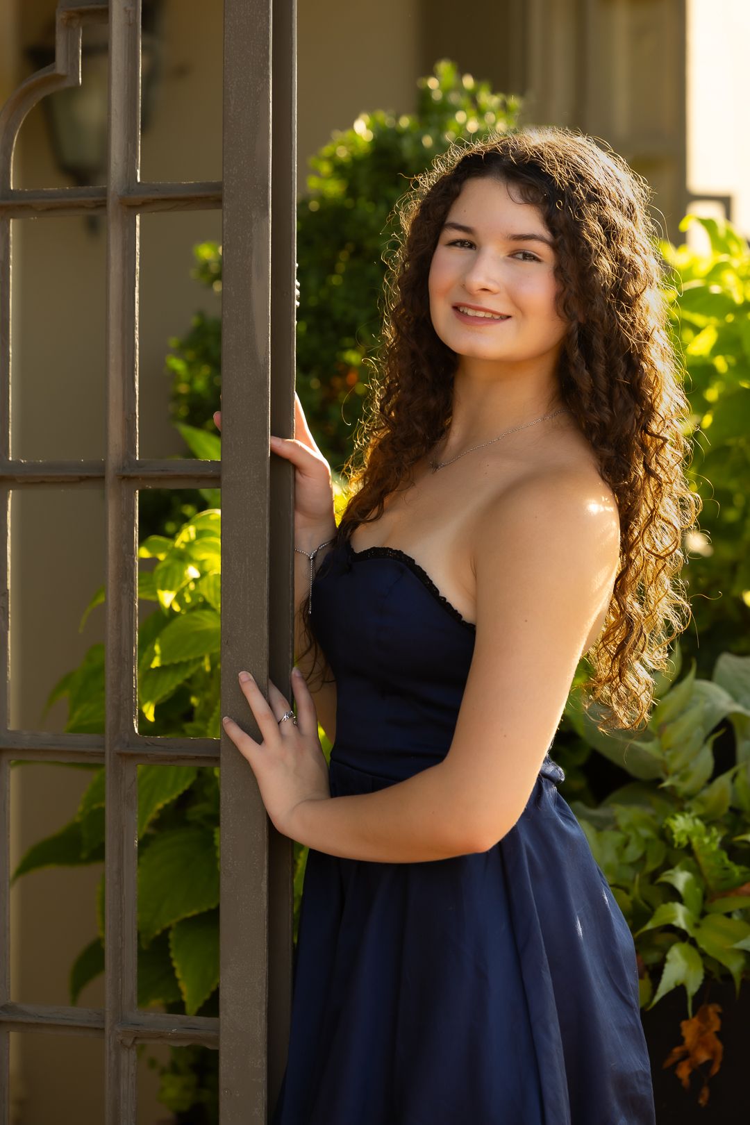 A series of outdoor portraits showing someone in a navy blue dress posing against a garden trellis in natural lighting.
