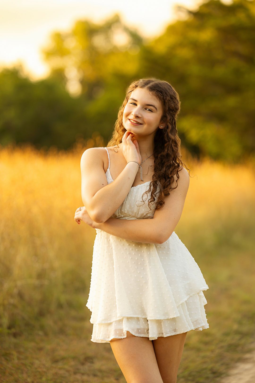 Golden hour portrait session in white flowy dress against sunset field.