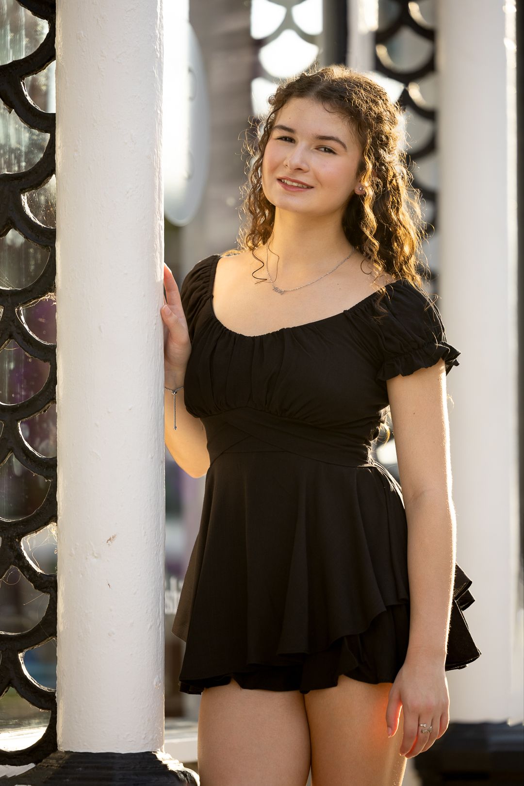 Portrait session featuring black ruffle dress against white architectural columns.