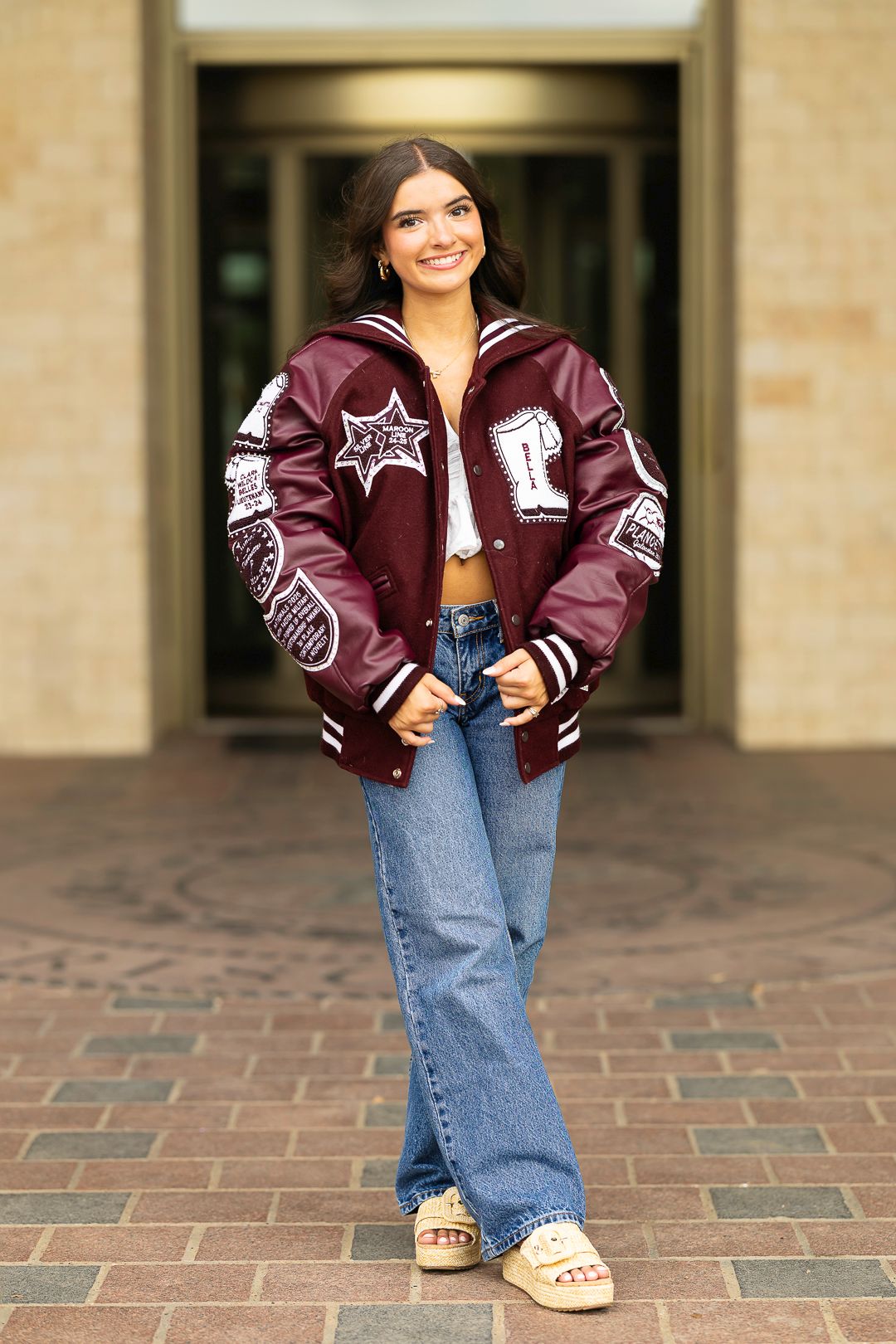 Senior photos in varsity letterman jacket and jeans. Urban setting.  Frisco Texas