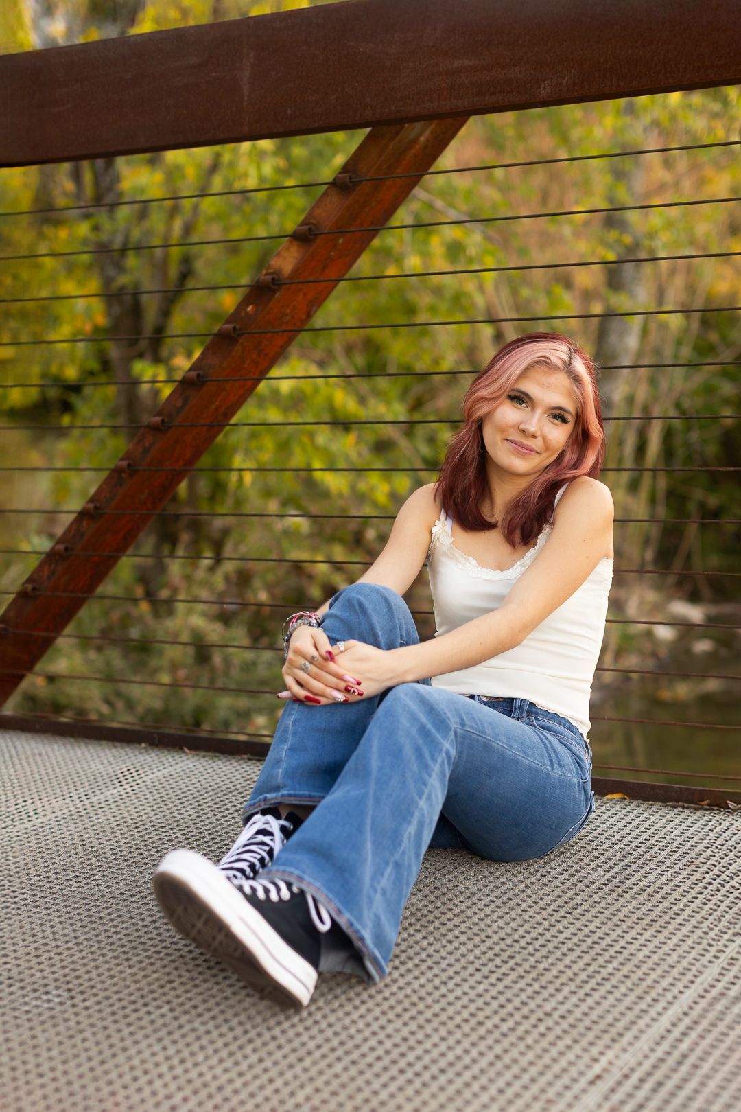 Casual portrait series on metal deck showing relaxed poses in jeans and sneakers.