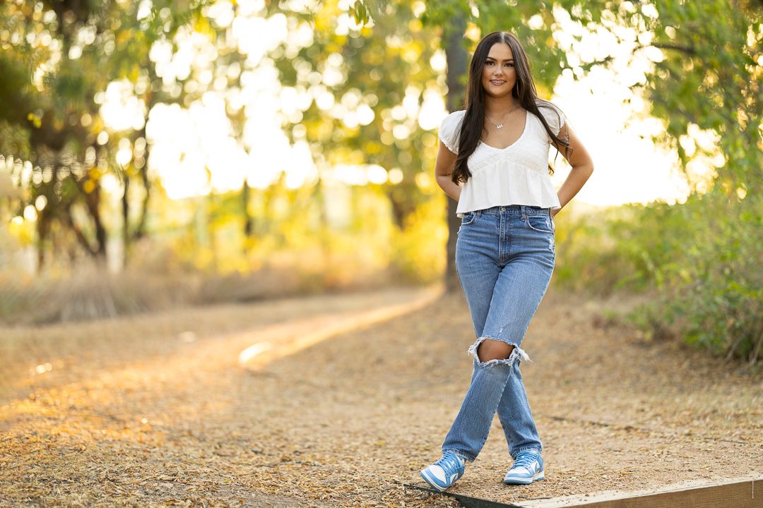 Outdoor portrait session in golden sunlight with jeans and casual styling.