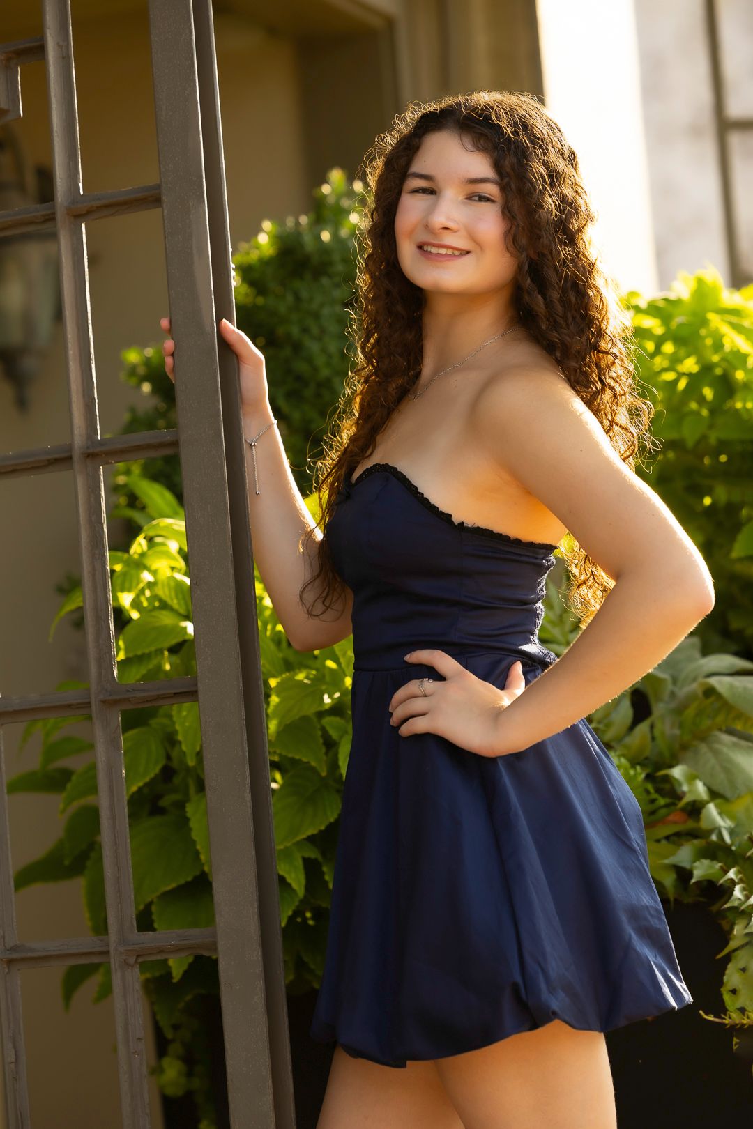 Summer portraits in navy blue ruffle top against garden trellis background.
