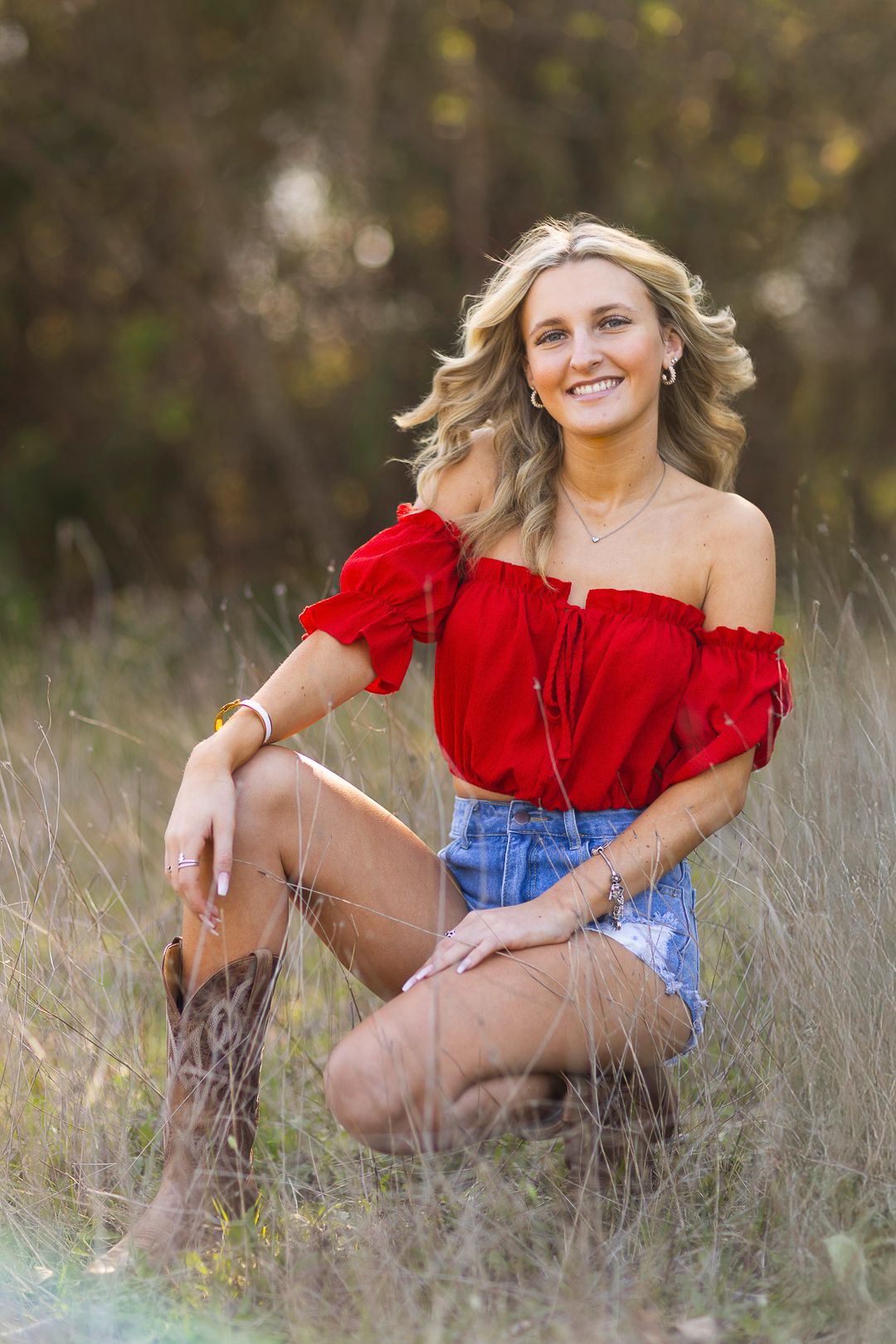 Senior Photos Fashion red crop top and denim shorts  tall grass during golden hour photoshoot. Limestone Quarry Park, Mckinney Texas