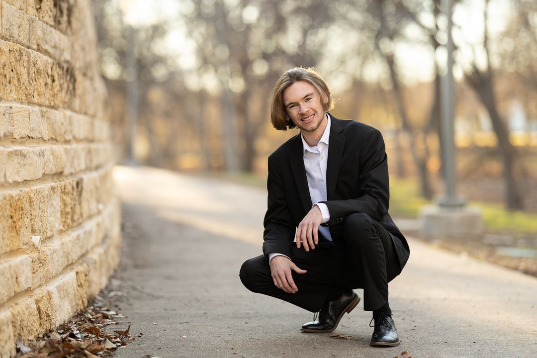 A person in a black suit poses outdoors against a stone wall in various professional portrait compositions.