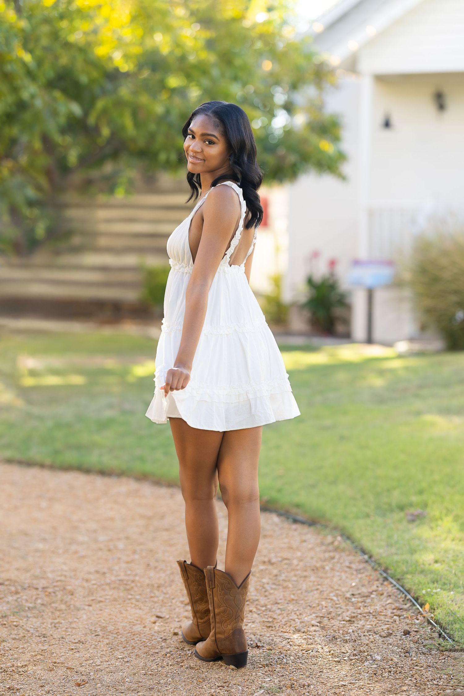 A person in a flowing white dress and brown boots poses outdoors against a natural backdrop in a series of artistic shots.