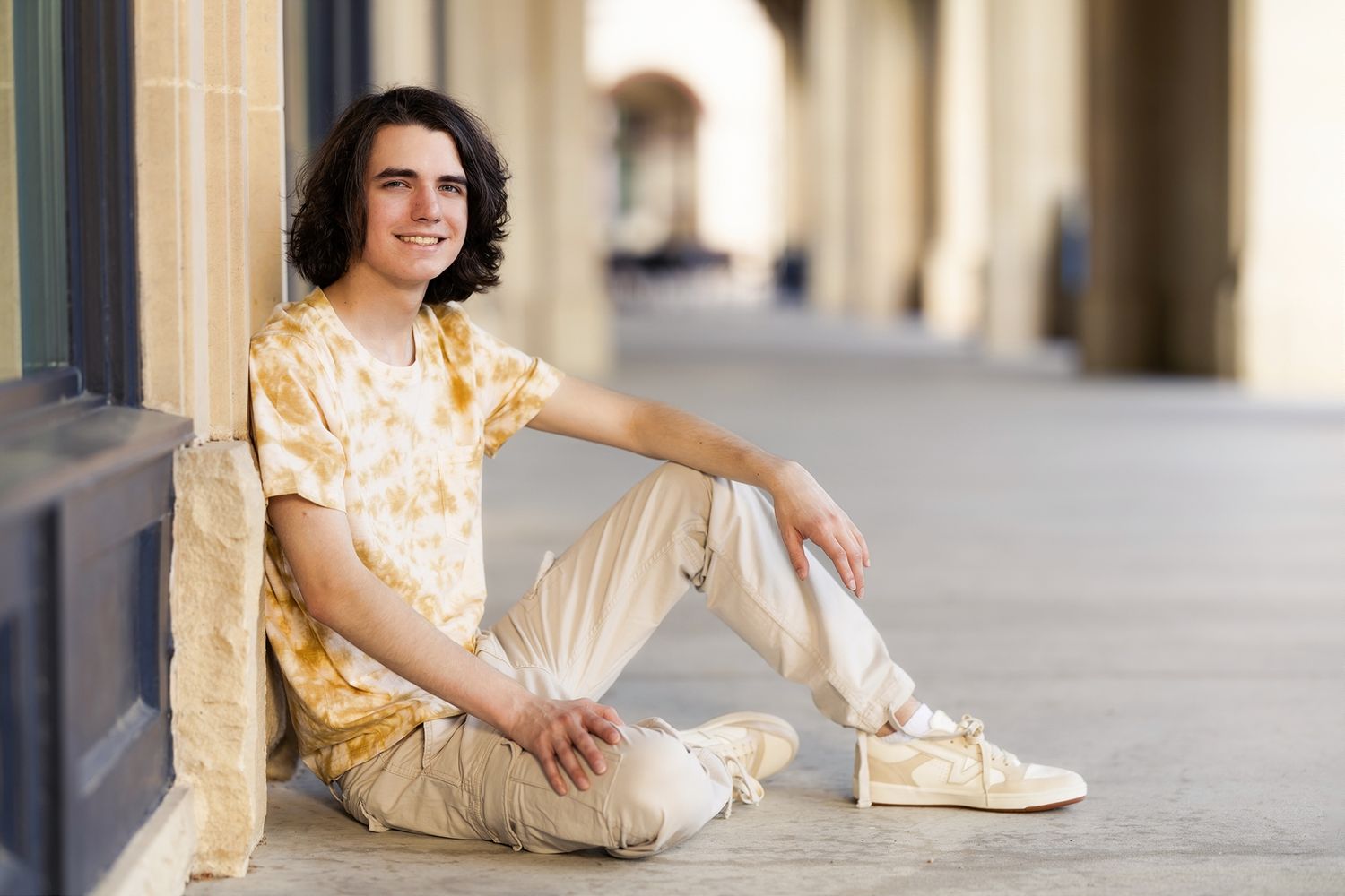 Person in casual attire sitting and posing against urban building walls in various relaxed positions.