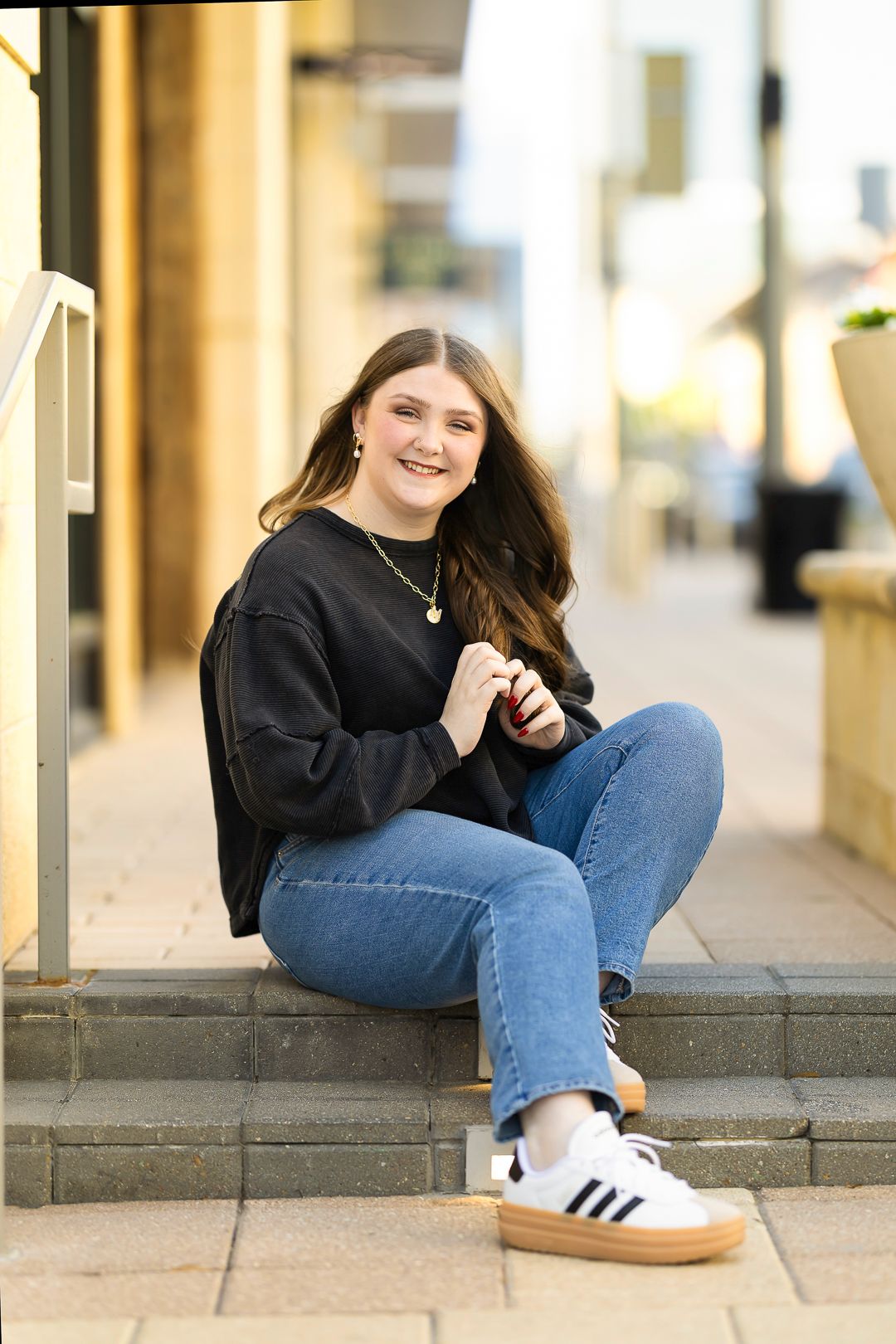 Urban portrait session on concrete steps wearing black sweater and denim.