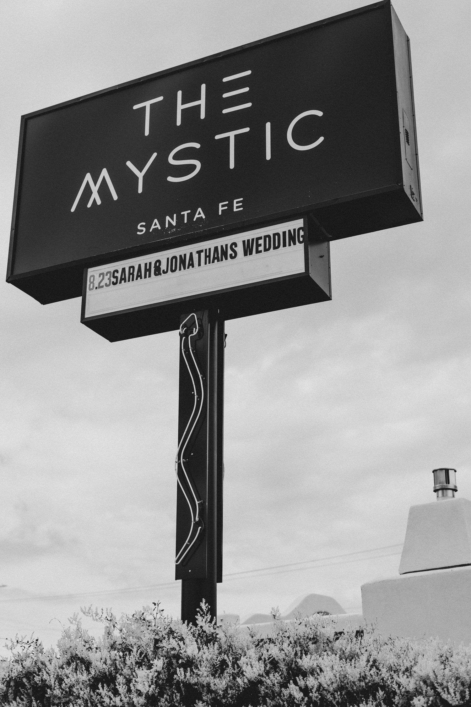 Black and white signage for The Mystic venue in Santa Fe displaying wedding event details.