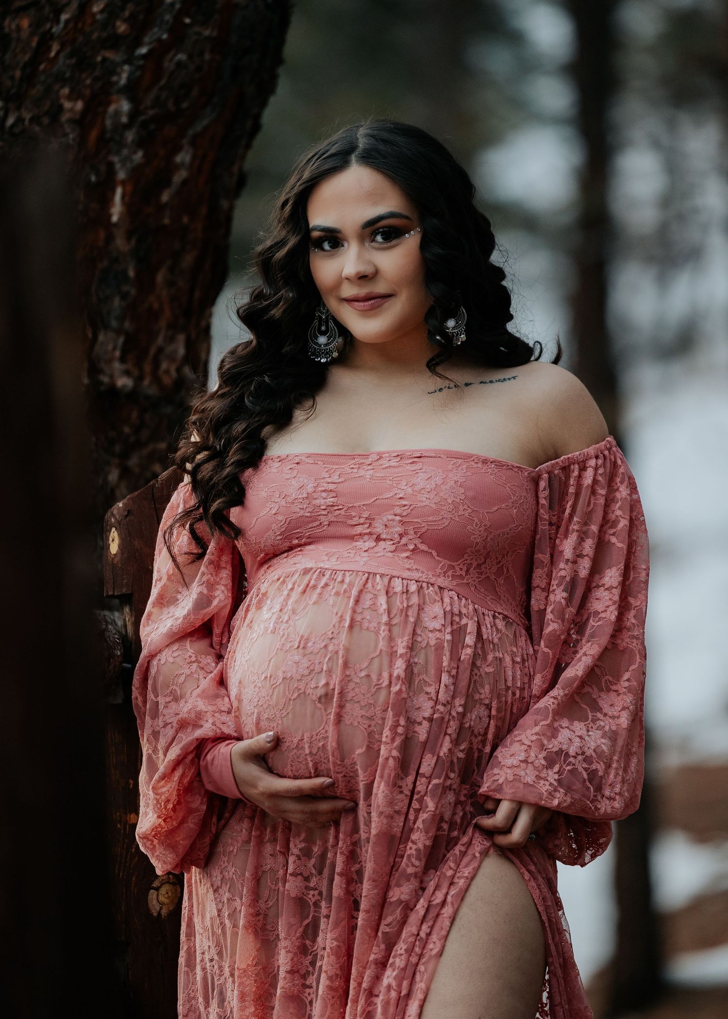 Person wearing romantic coral off-shoulder dress poses elegantly against snowy forest backdrop.