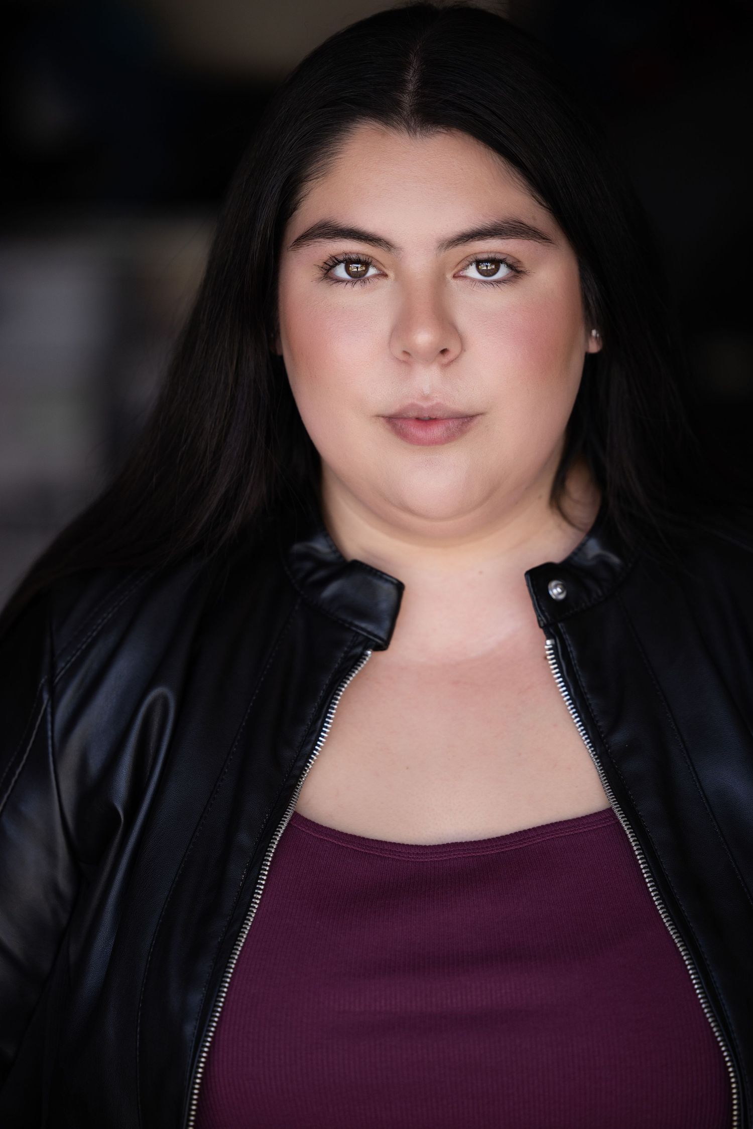 Portrait series in black jacket and burgundy top with natural lighting.