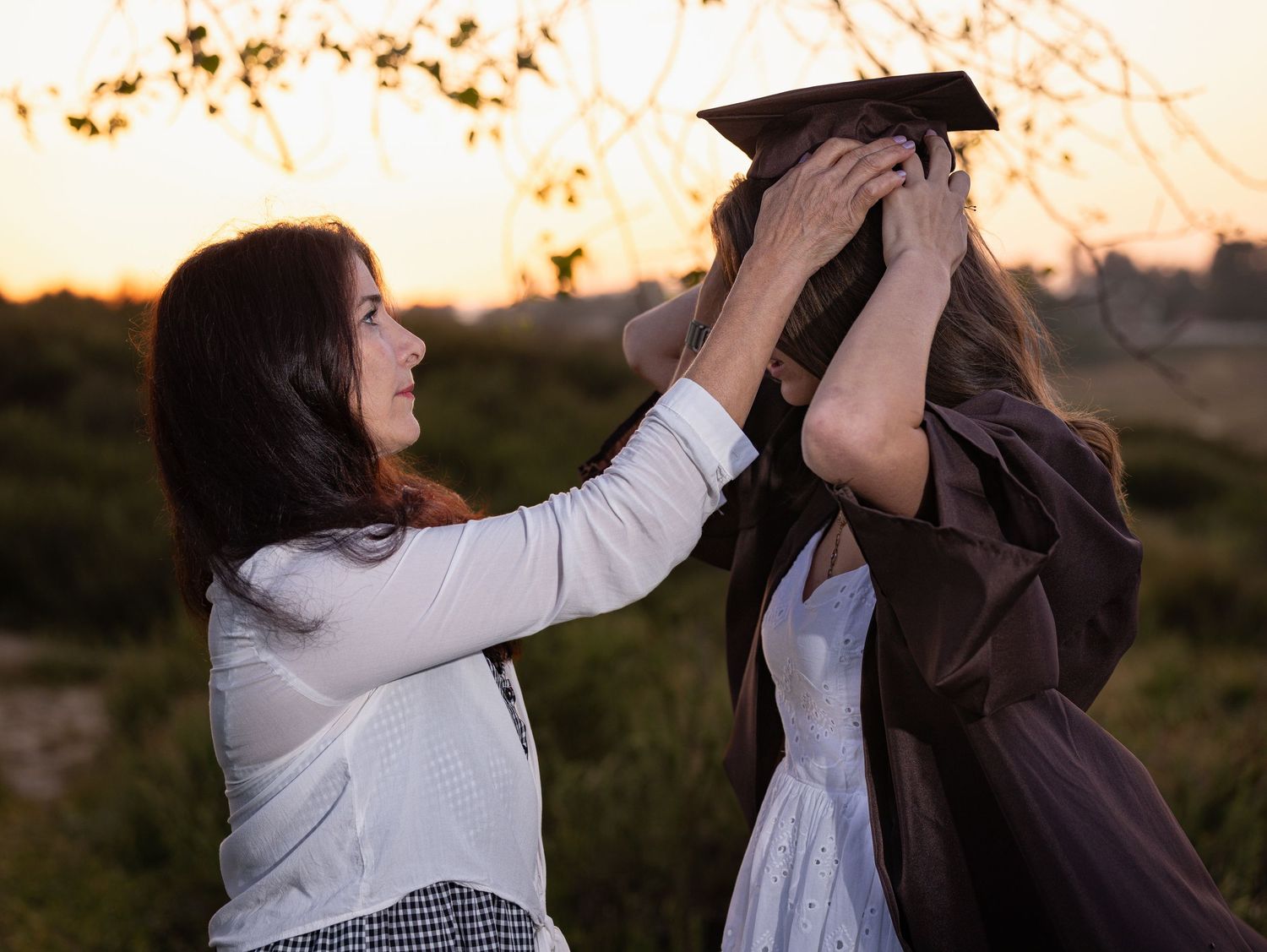 A couple in white and black outfits dance together during golden hour in an outdoor setting.