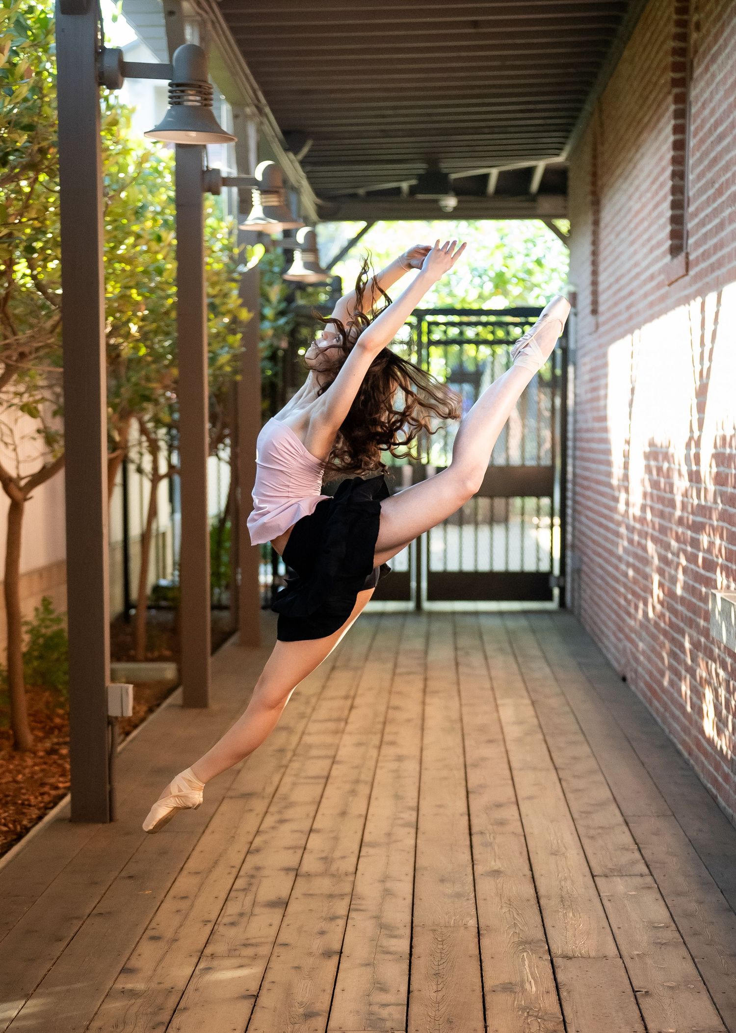 Series of dynamic dance poses captured in a sunlit corridor with wooden floors and brick walls.