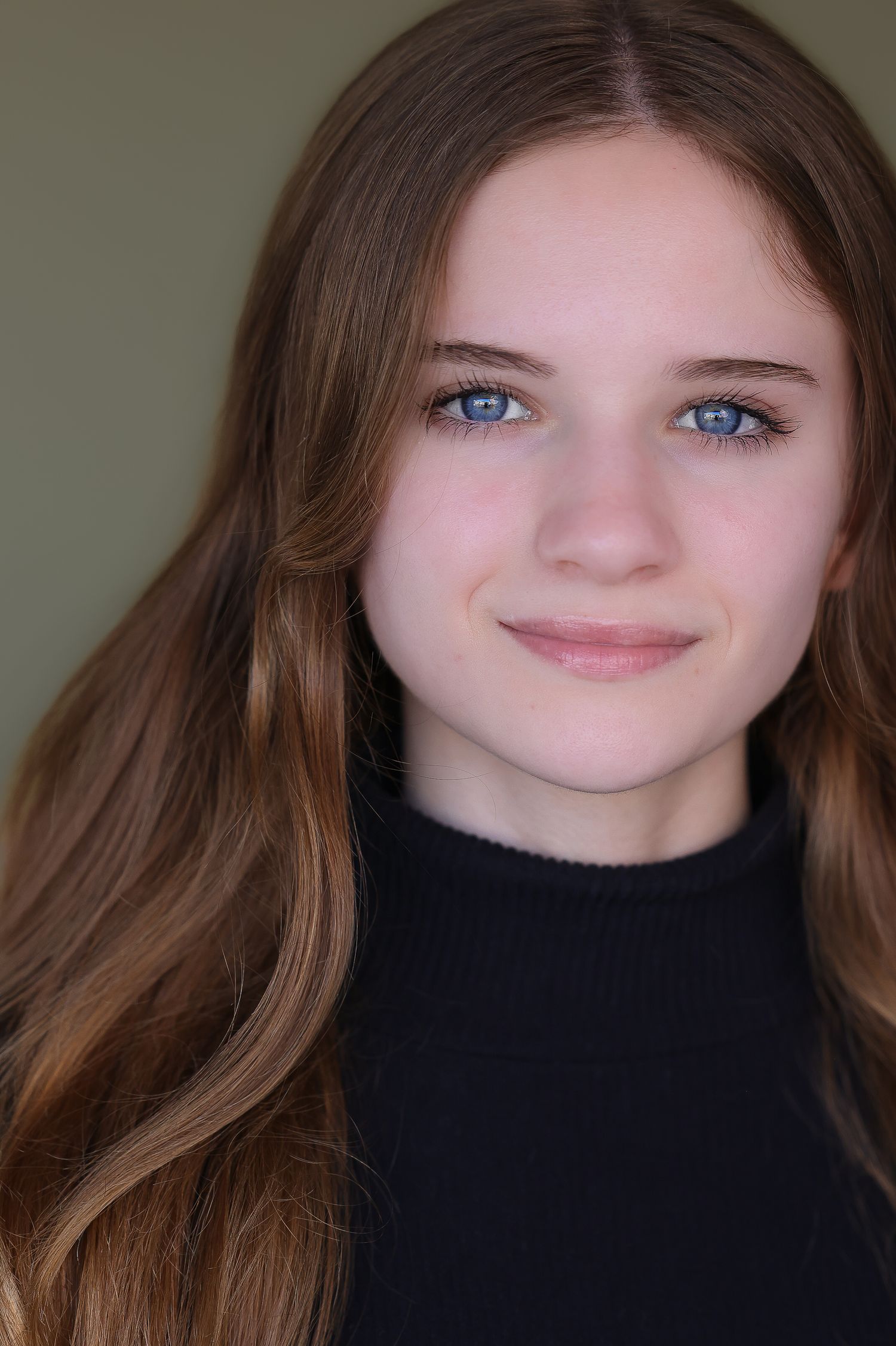 Close-up portrait wearing black turtleneck against dark background.