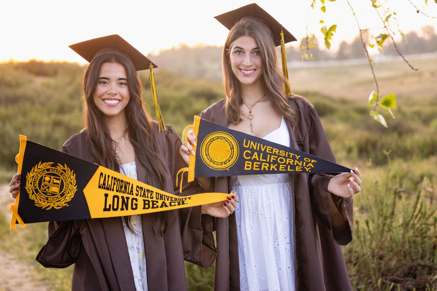 A college graduate displays a University of California Berkeley pennant during golden hour graduation photos.