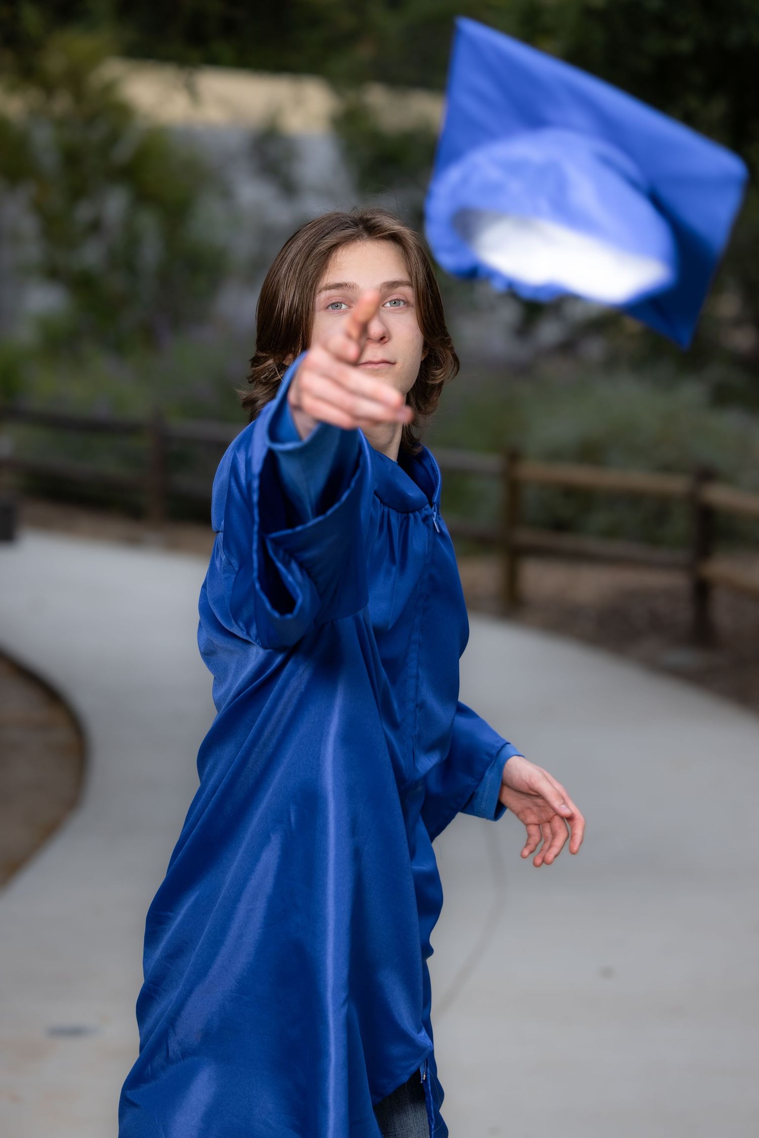 Person in bright blue raincoat spins and dances playfully outdoors on a cloudy day.