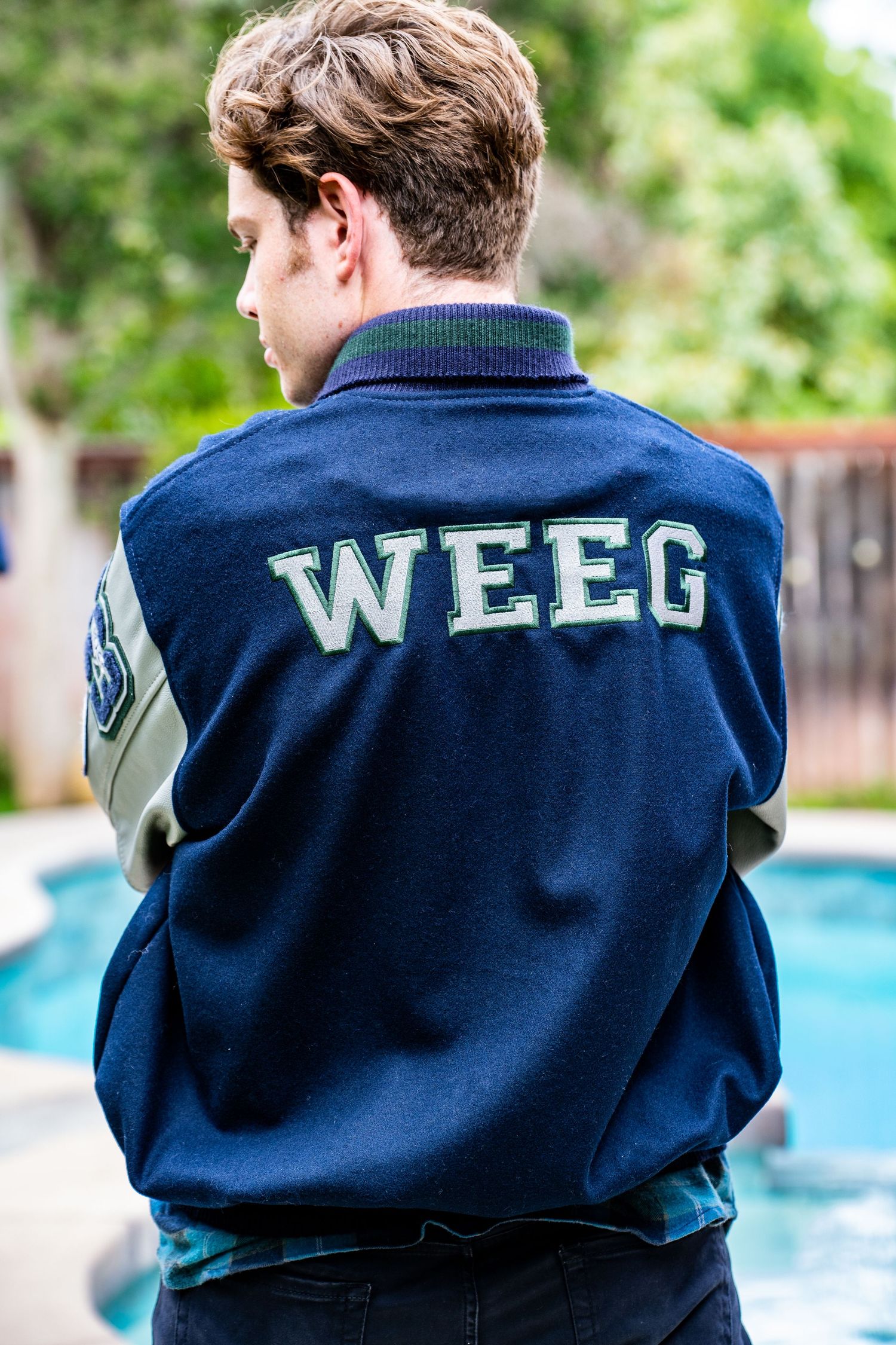 A navy blue sweatshirt with 'WEEG' text on the back is shown from multiple angles near a swimming pool.