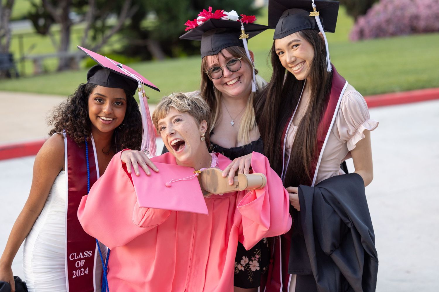 A group of friends wearing pink and black outfits pose together outdoors during a celebration.