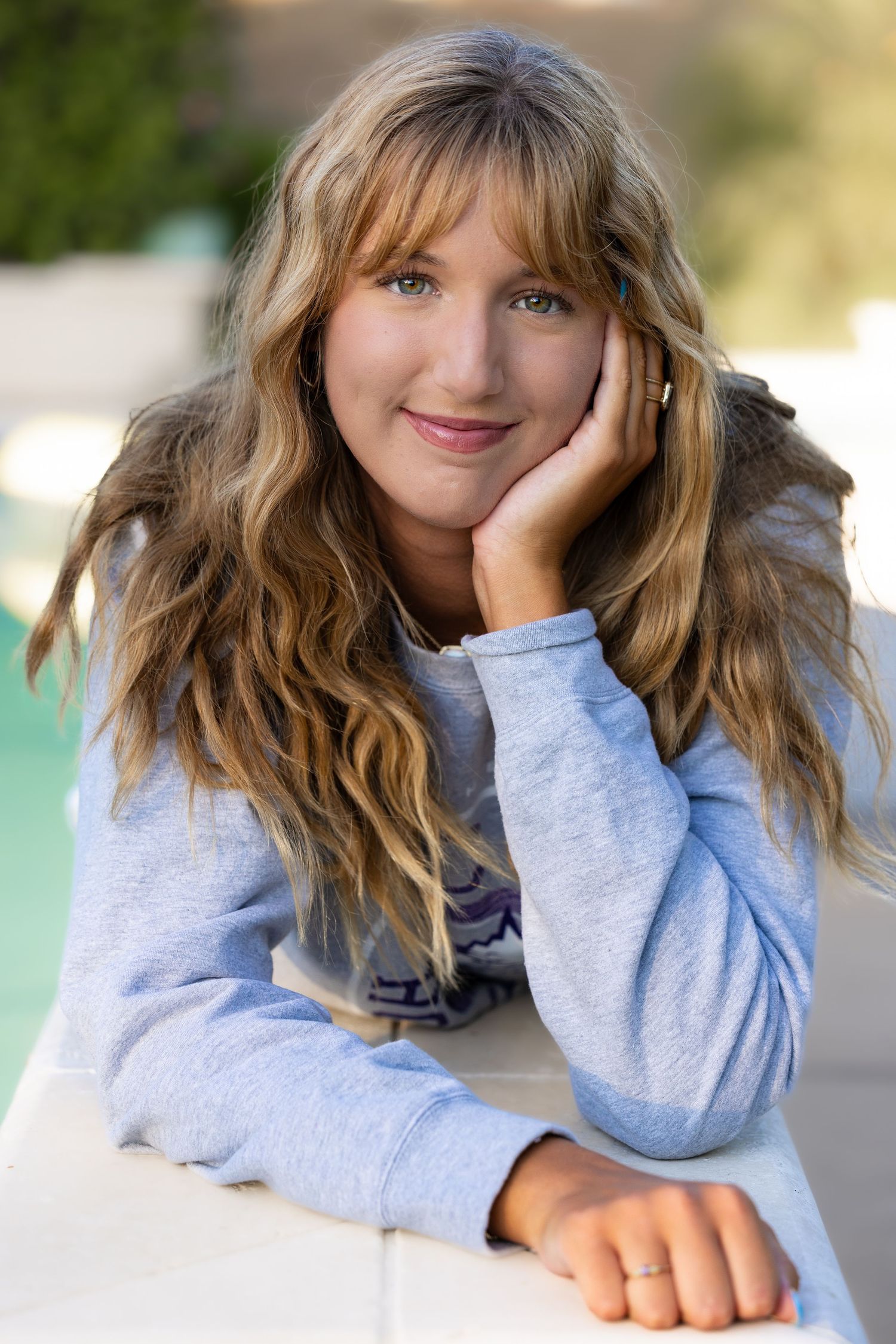A series of five candid portraits showing a person in a light blue hoodie with wavy hair in different playful poses.