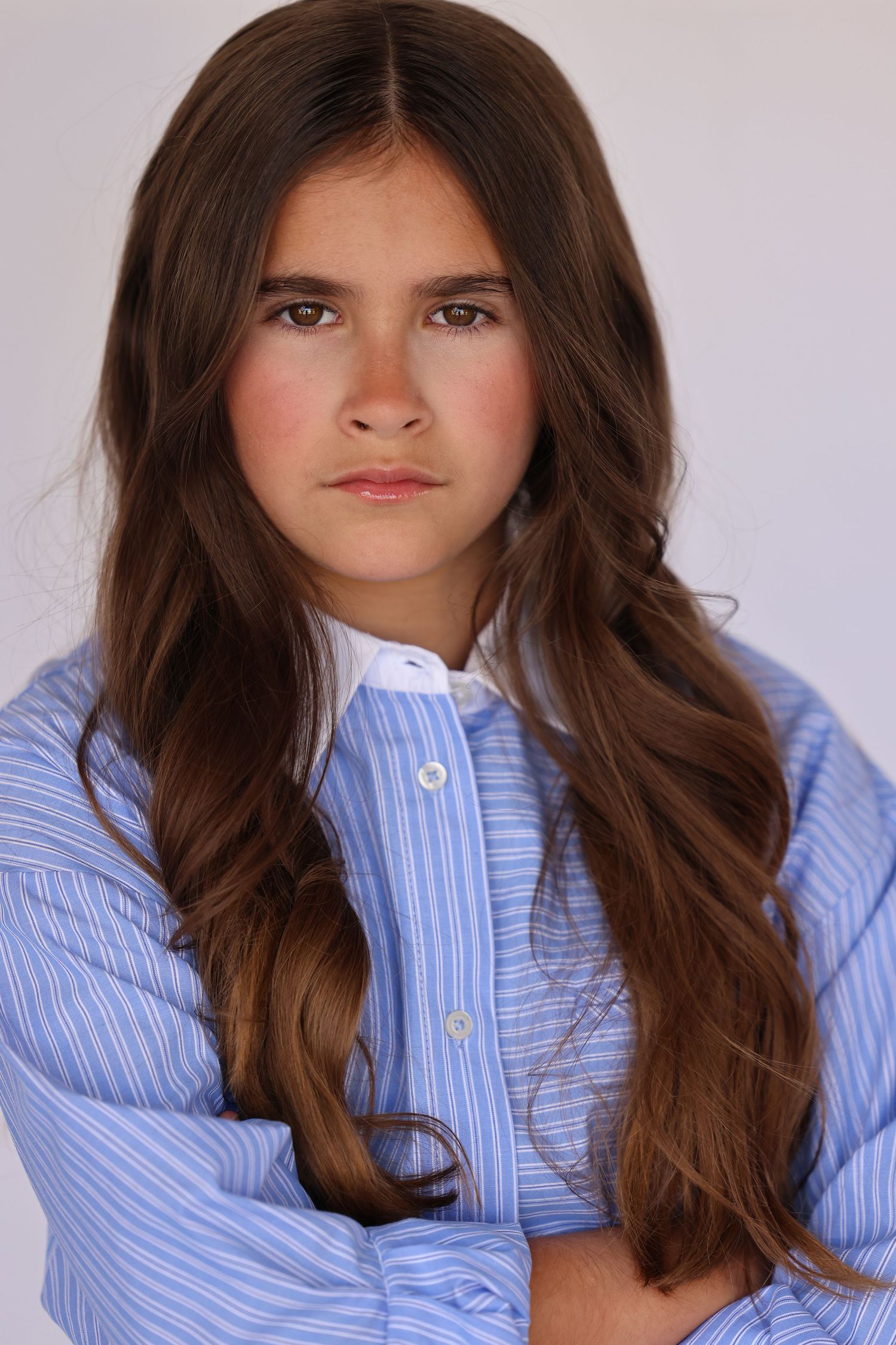 Portrait in light blue pinstripe button-up shirt against white background.