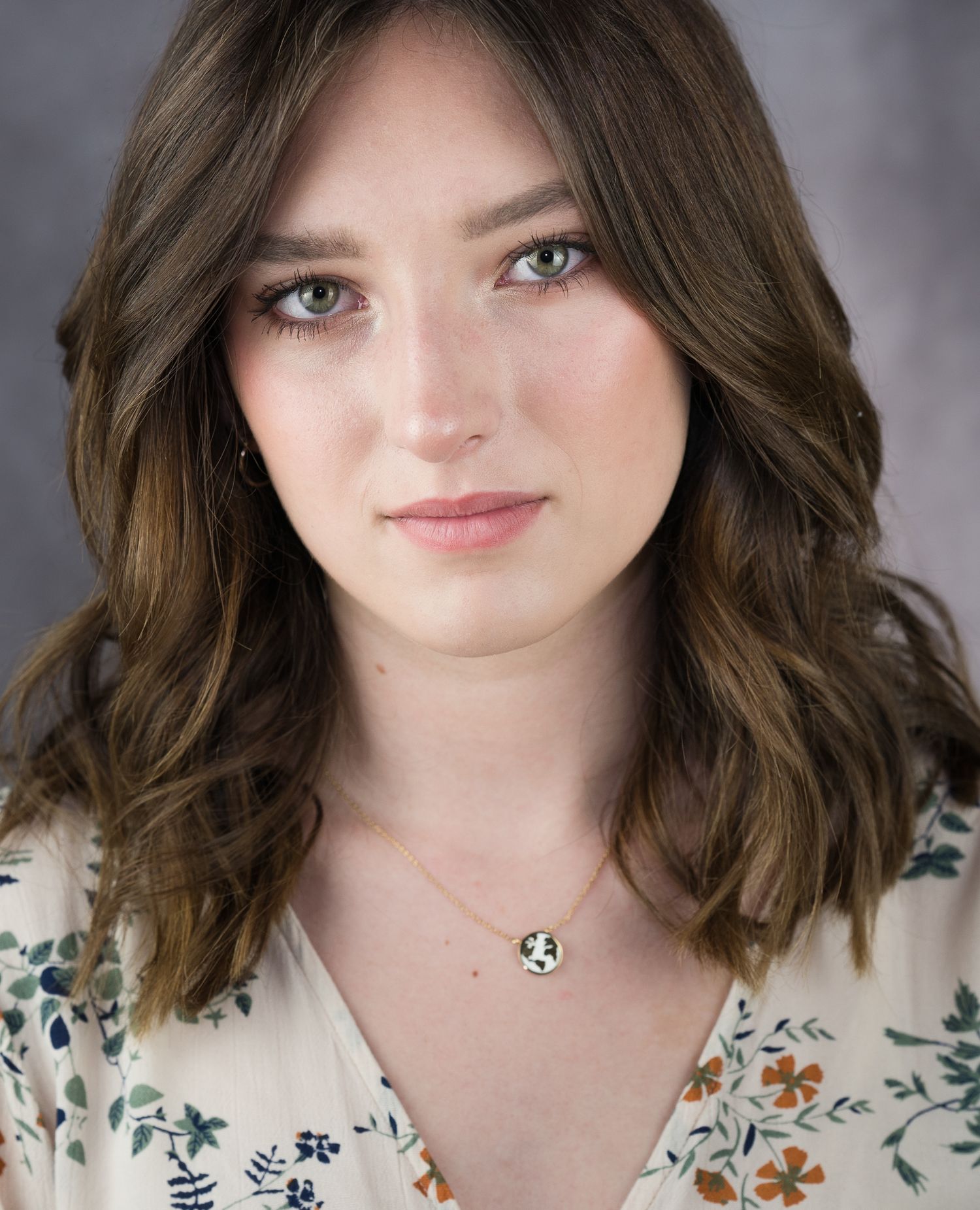 A person wearing a white floral print top shows various expressive facial poses against a gray studio background.