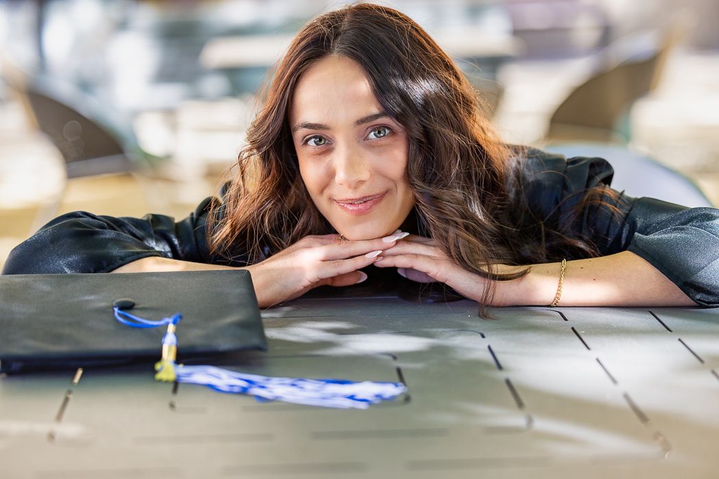 Person with long dark hair resting on wooden table with paperwork nearby.
