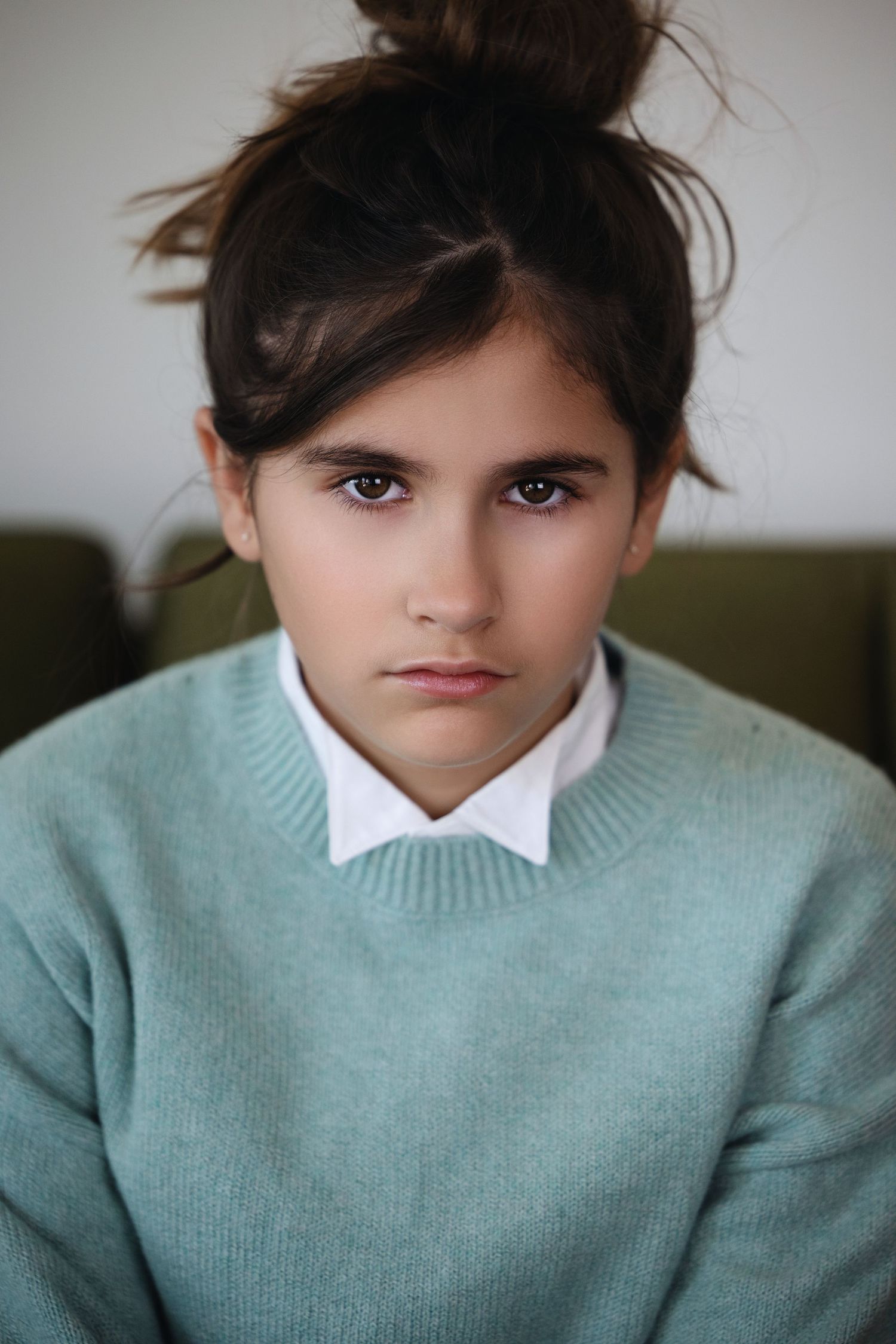 Portrait in mint green sweater with white collar against light background.