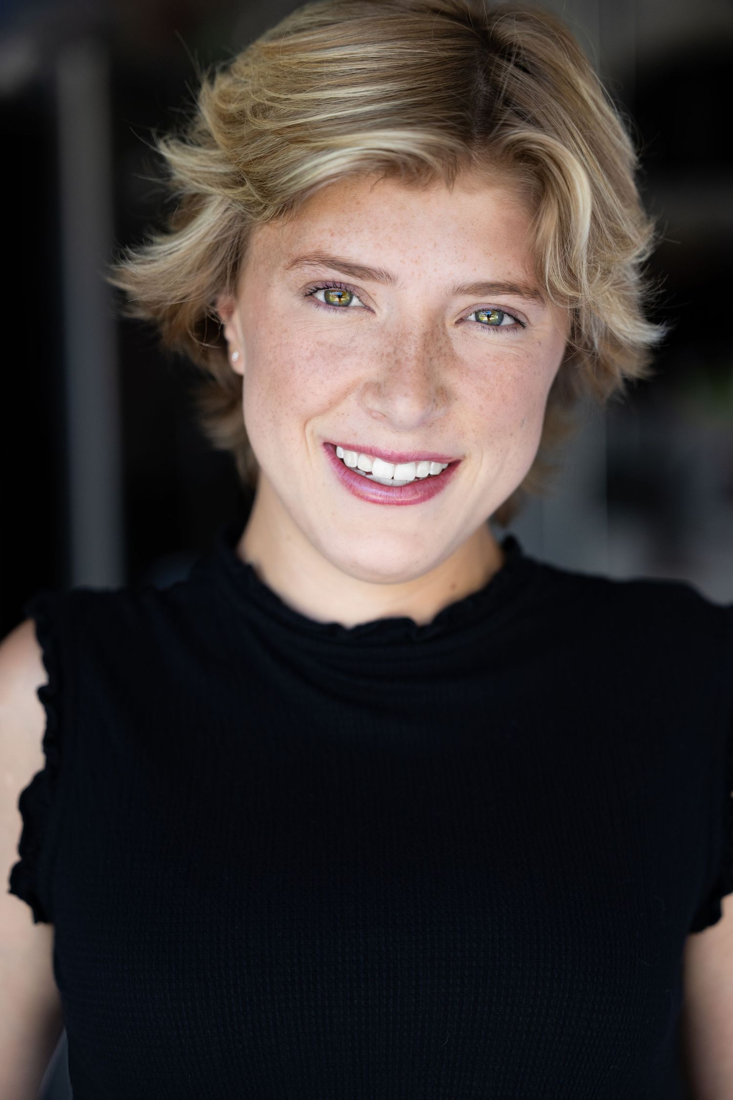 18TPY headshot. Headshot series in black top showing joyful expressions against dark backdrop.