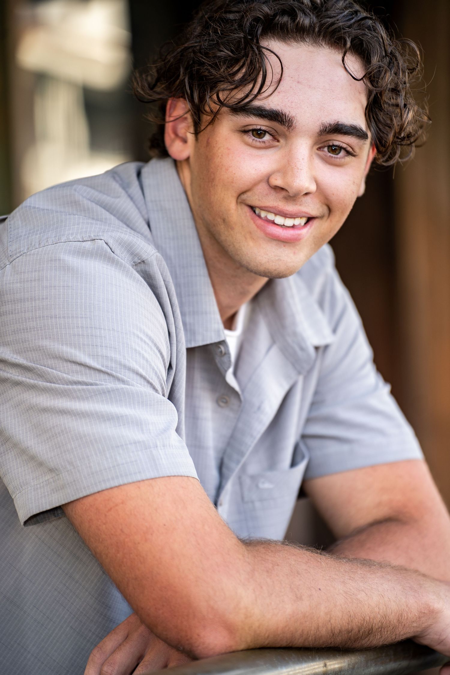 Professional headshot of a young person in a light gray polo shirt smiling warmly against a blurred background.