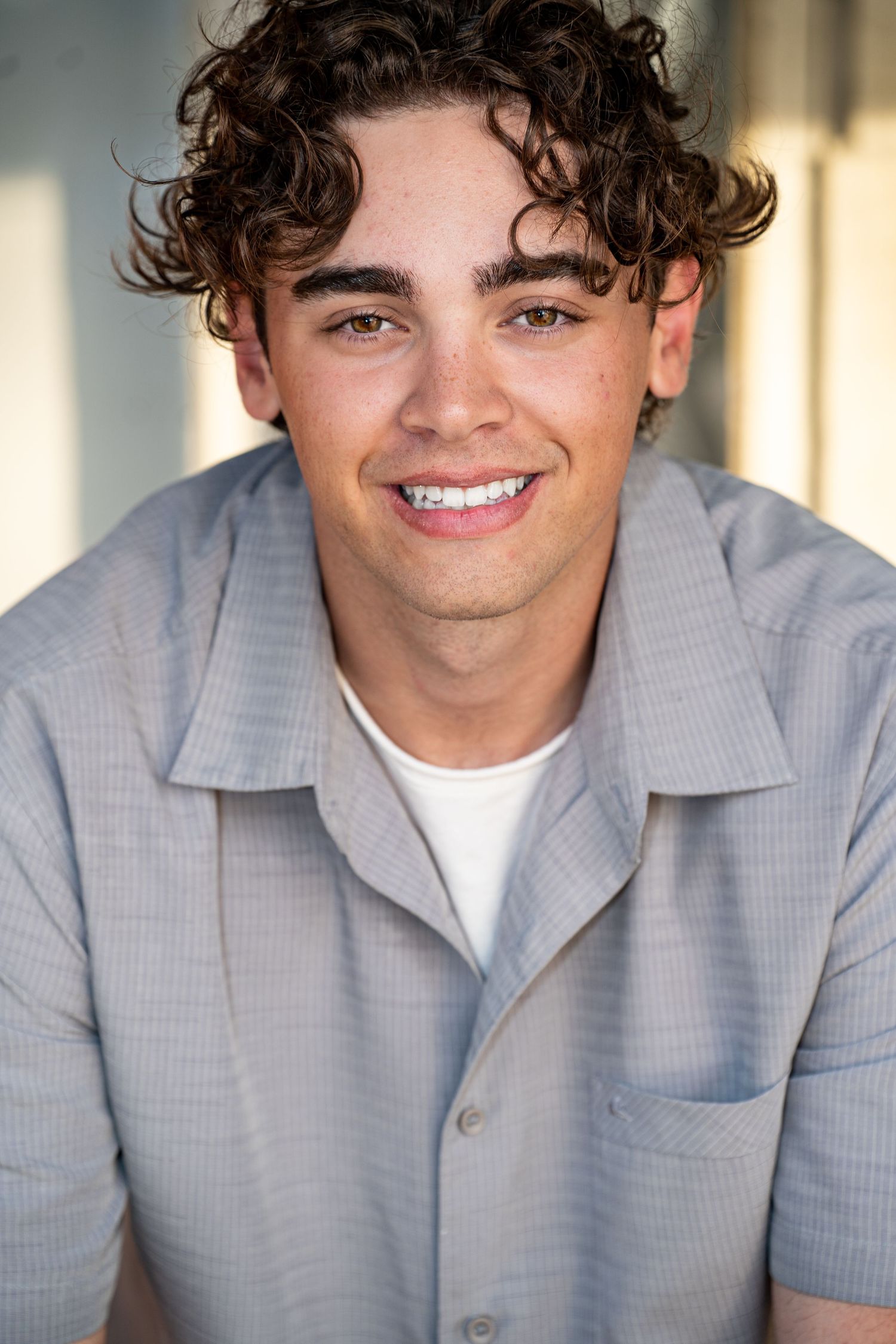 teen boy headshot outdoors. A person wearing a gray button-down shirt smiles at the camera in a series of four similar portrait shots.
