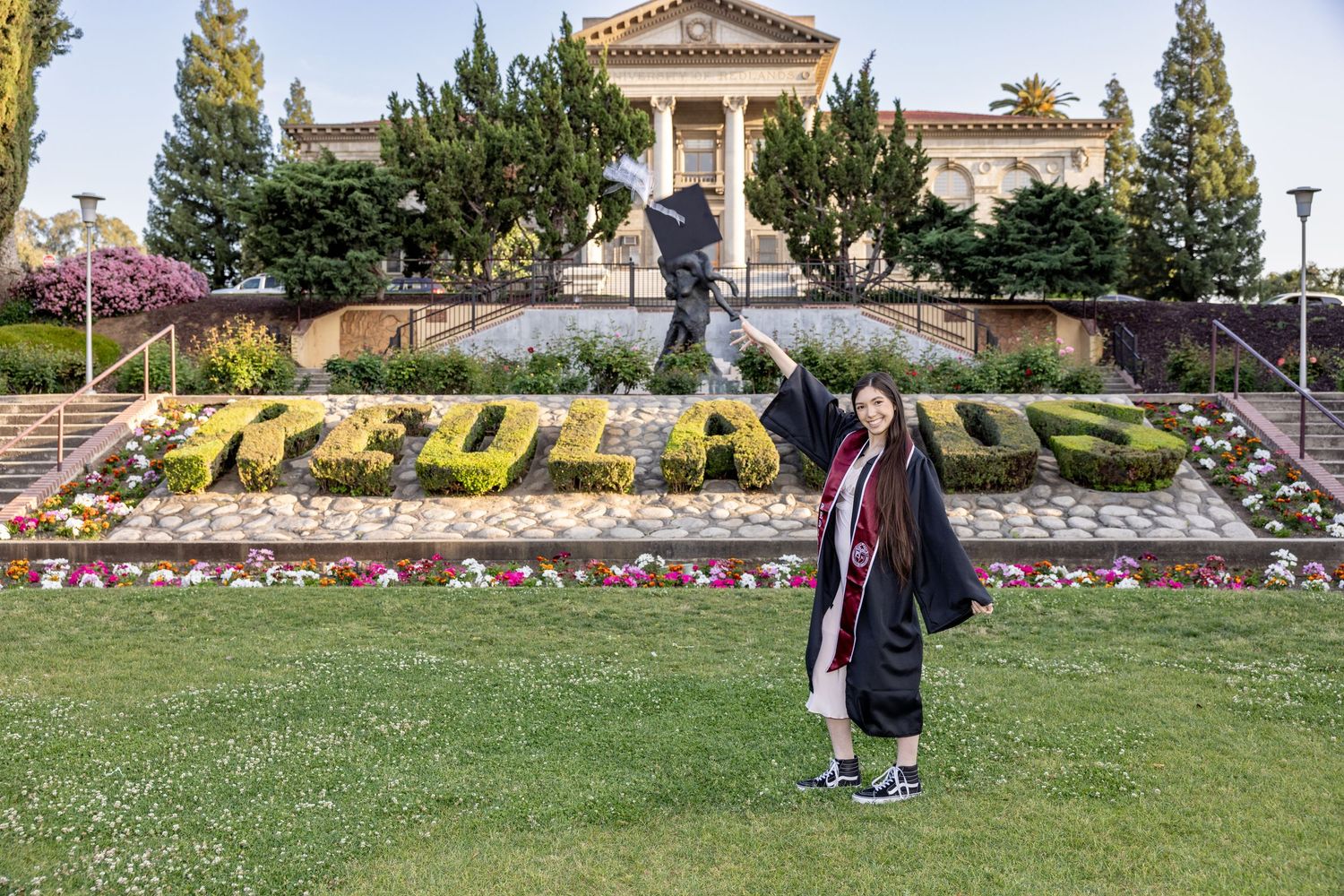 A series of colorful floral displays and landscaping arrangements spell out 'CSULB' on a grassy hillside.