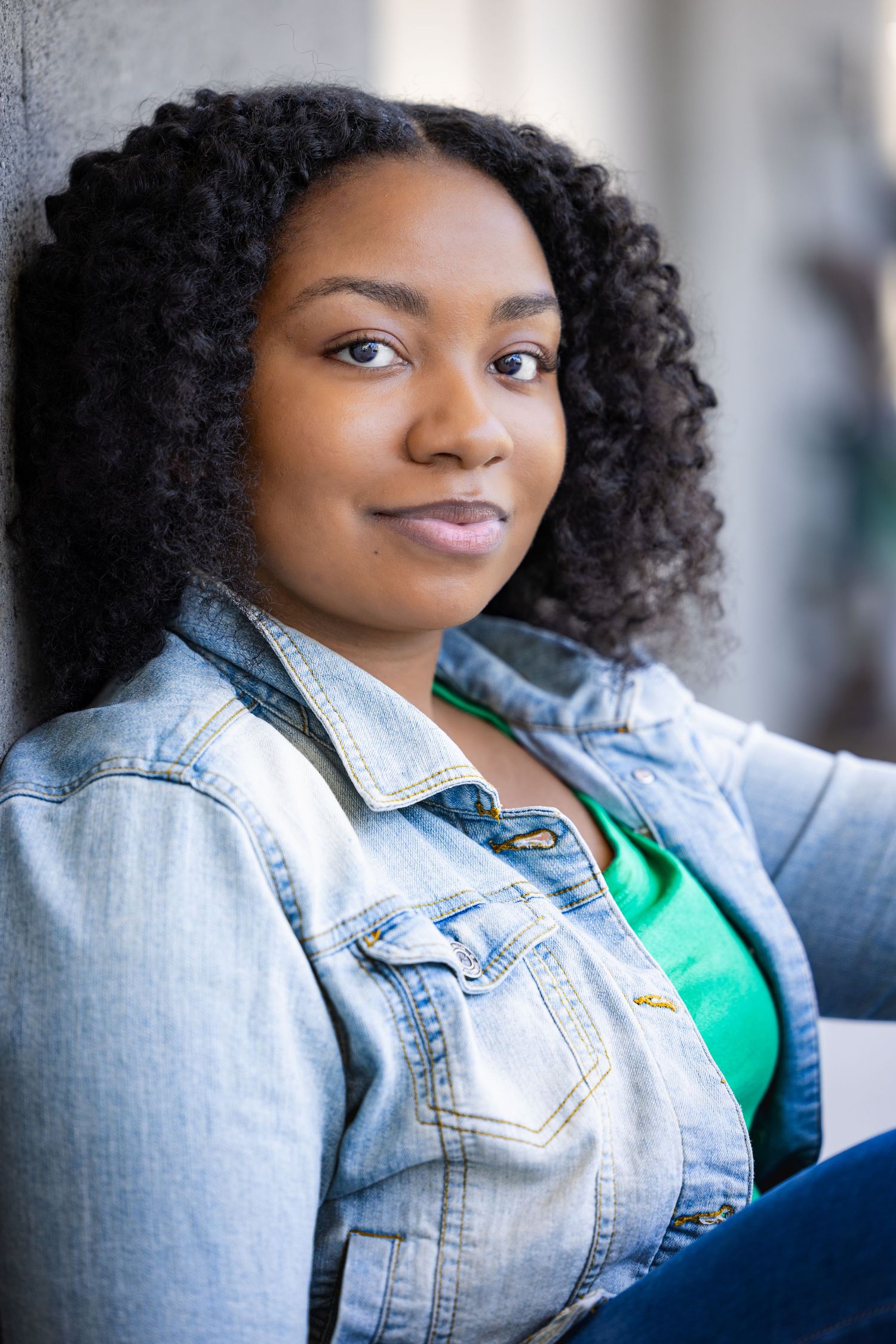 A series of four photos showing someone wearing a denim jacket and green top with natural curly hair in different poses.
