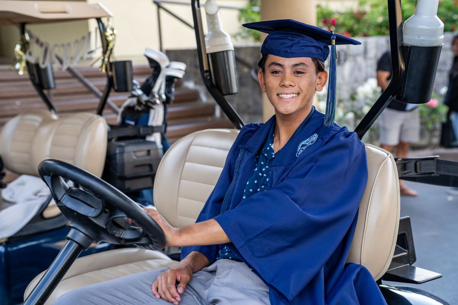 Golf cart drivers in blue uniforms smile while seated in their vehicles.