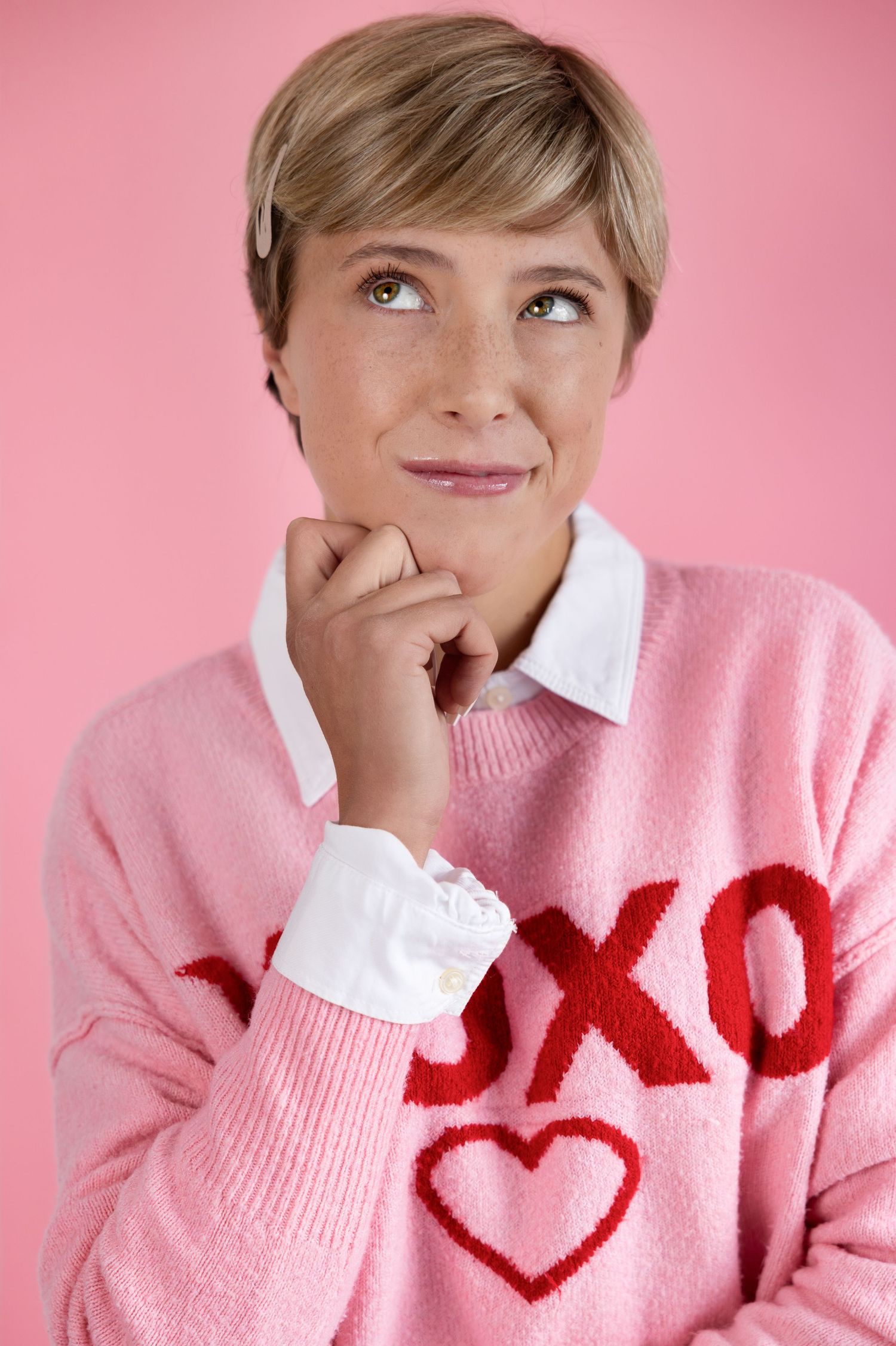 commercial headshot. Playful expressions in pink sweater with red design against pink background.