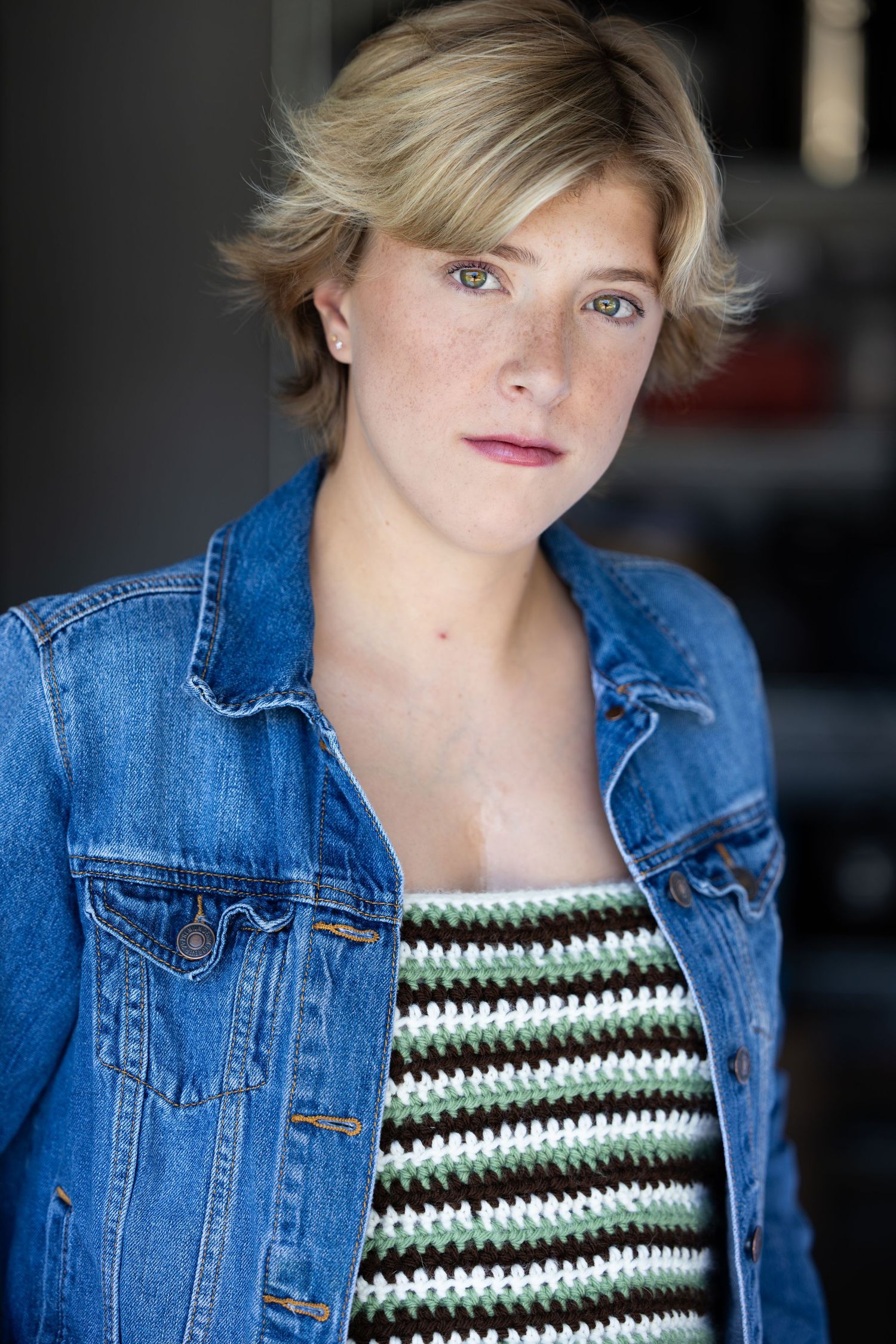 A person wearing a denim jacket and striped top poses against a dark background in a series of headshots.