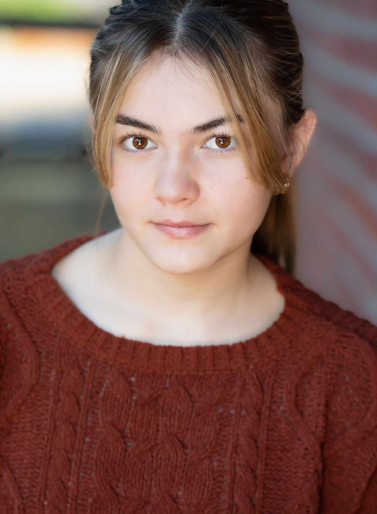 Close-up headshot of person wearing a burgundy knit sweater with natural lighting and soft focus.