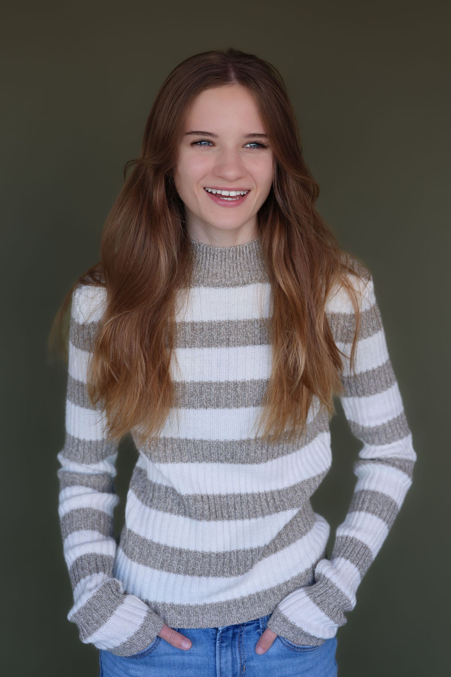 all American girl headshot. Casual pose wearing striped gray and white sweater with jeans.