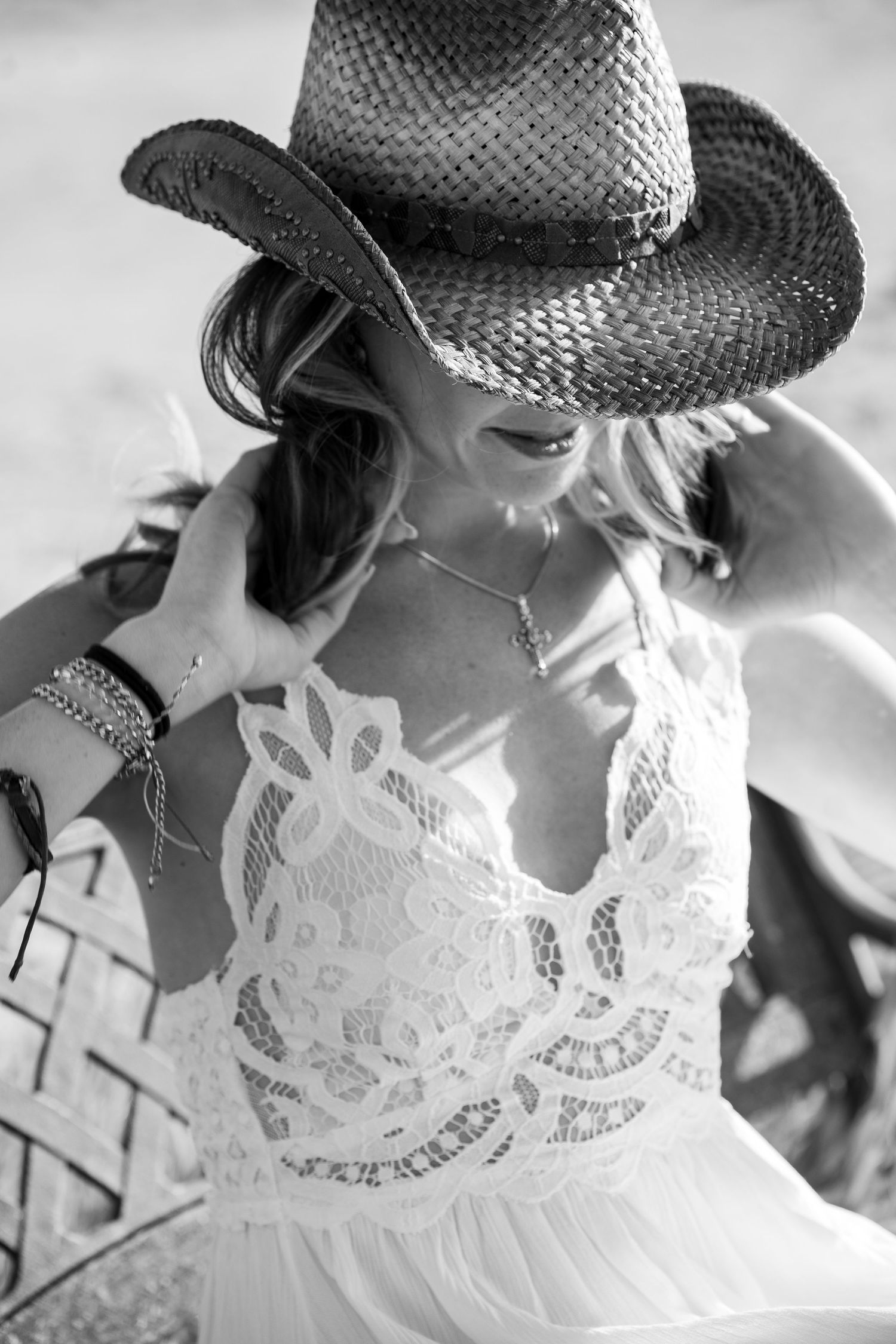 Black and white portrait of someone in a cowboy hat and white lace dress in soft natural lighting.