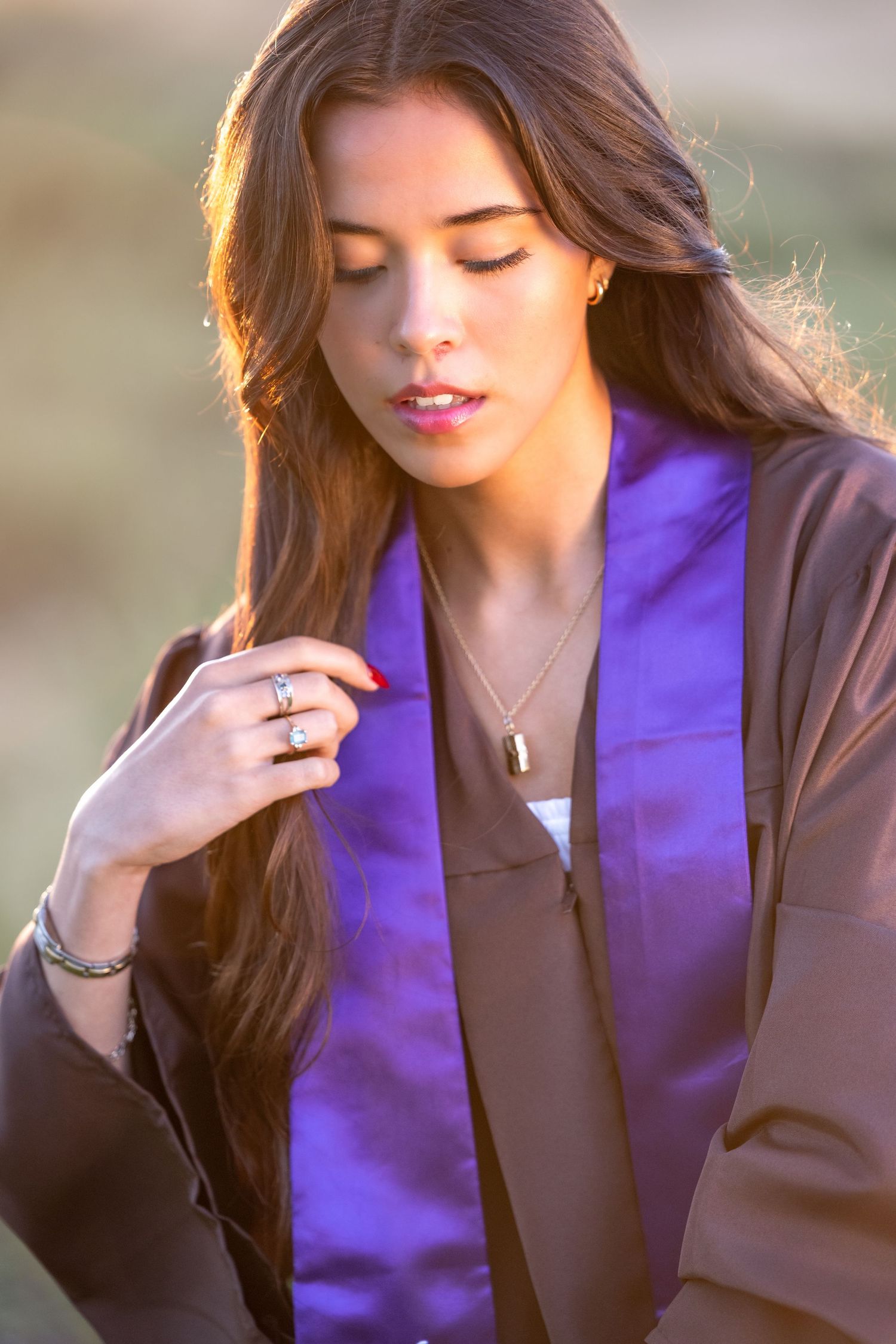 Model in a purple blazer and dark jacket poses elegantly in a soft sunlit outdoor photoshoot series.