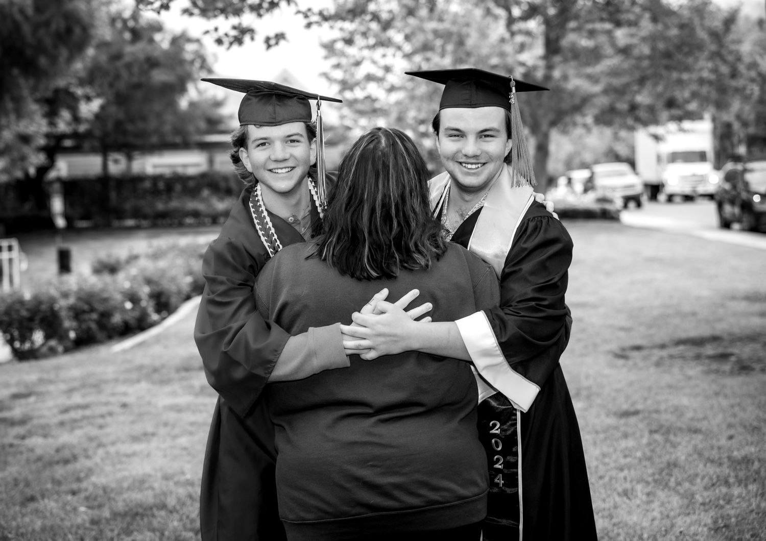 Black and white graduation photos showing joyful embraces and celebrations between graduates in caps and gowns.