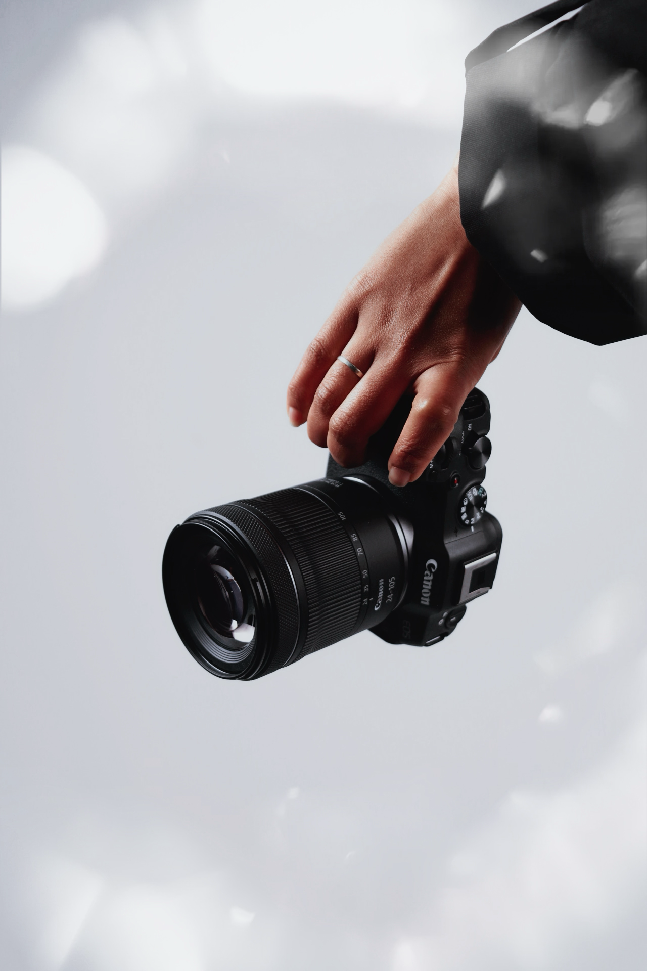 Close-up shots of hands holding professional camera lens against bright background.