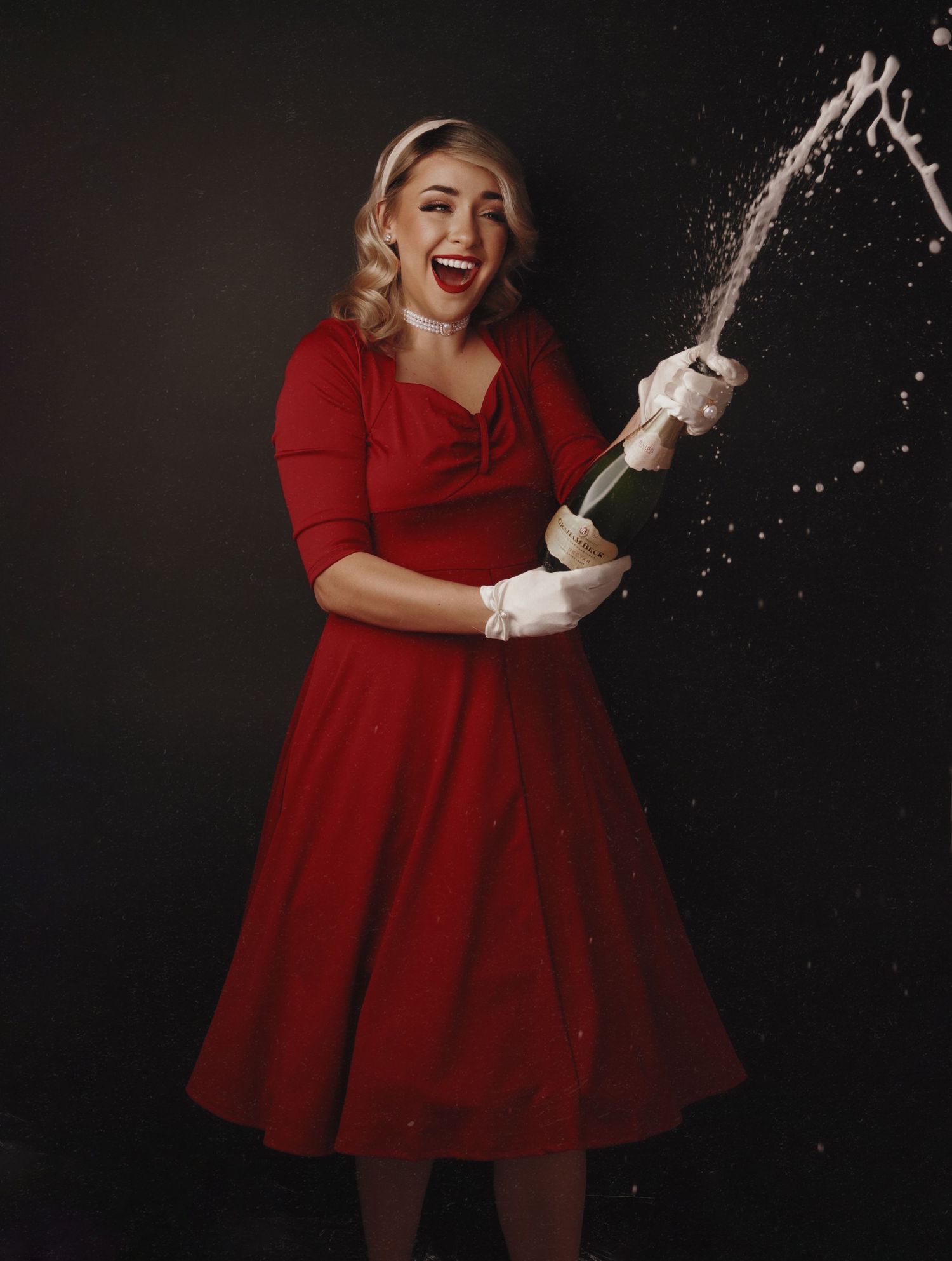 Playful scene showing someone in a red dress throwing flour or powder in a vintage-style photoshoot.