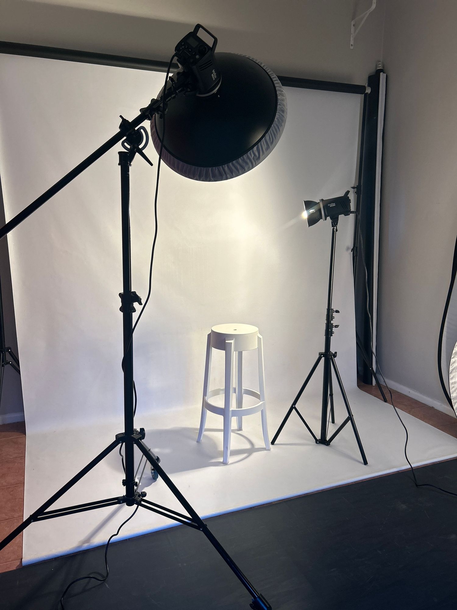 Empty photography studio interior showing lighting equipment and setup against white walls.