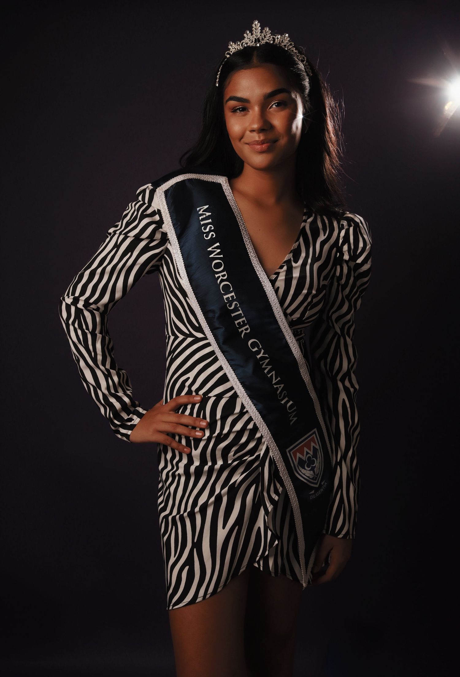 Fashion photos showing zebra print blazer and pageant sash in dramatic studio lighting.