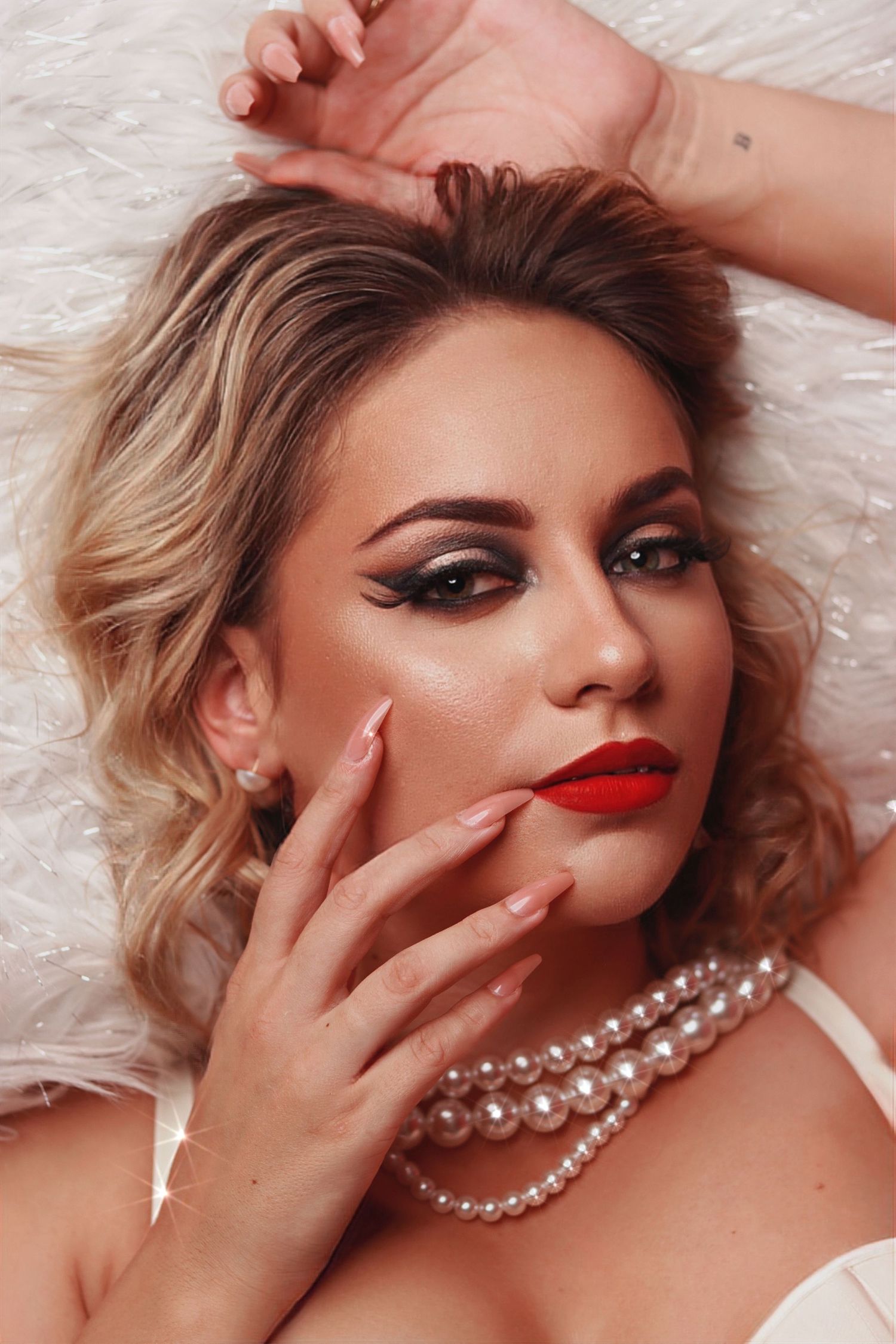 Sensual boudoir sequence showing dramatic makeup and pearl jewelry against light backdrop.
