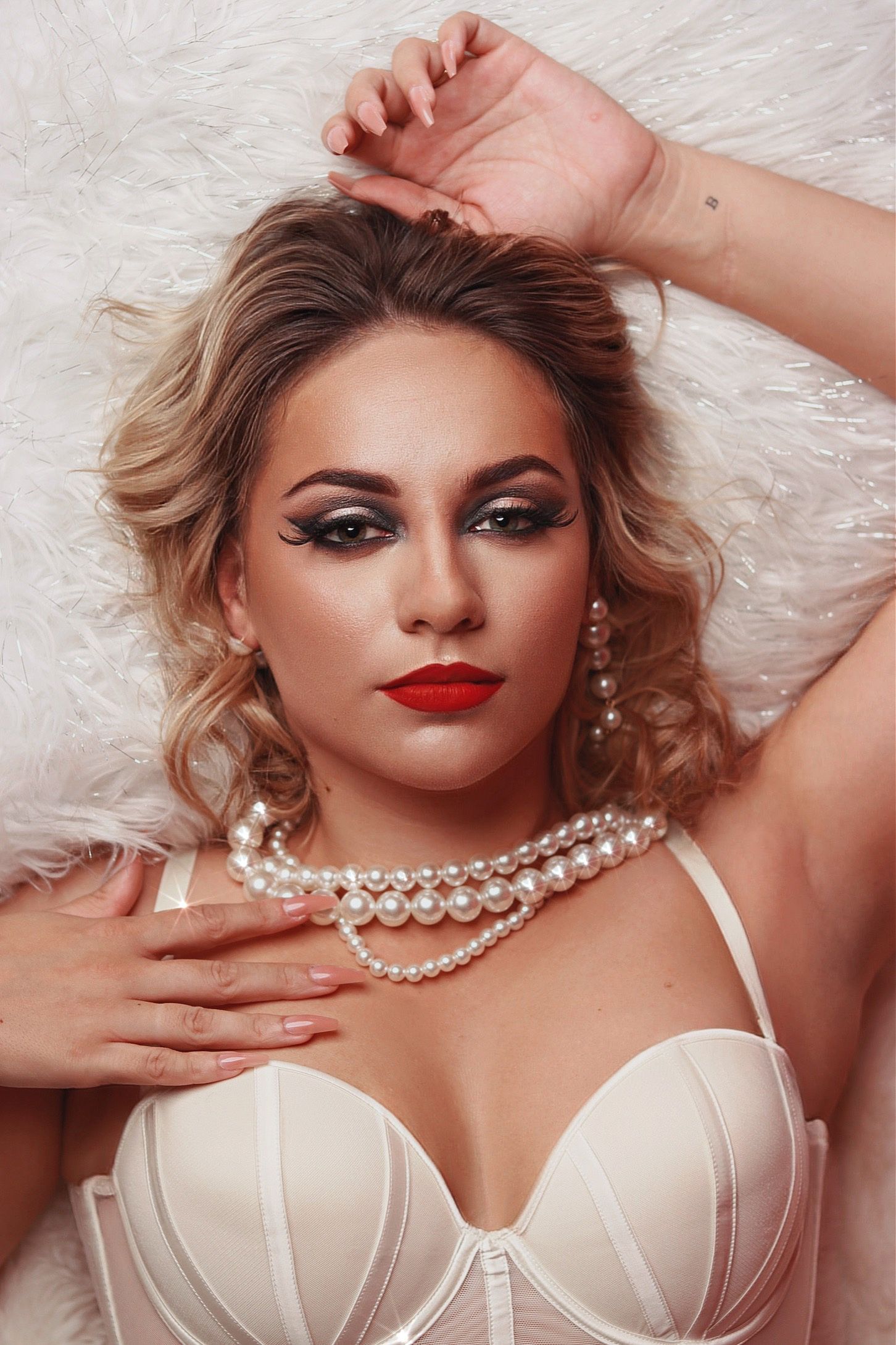 Glamour photos featuring pearl necklace and white lingerie against furry white background.