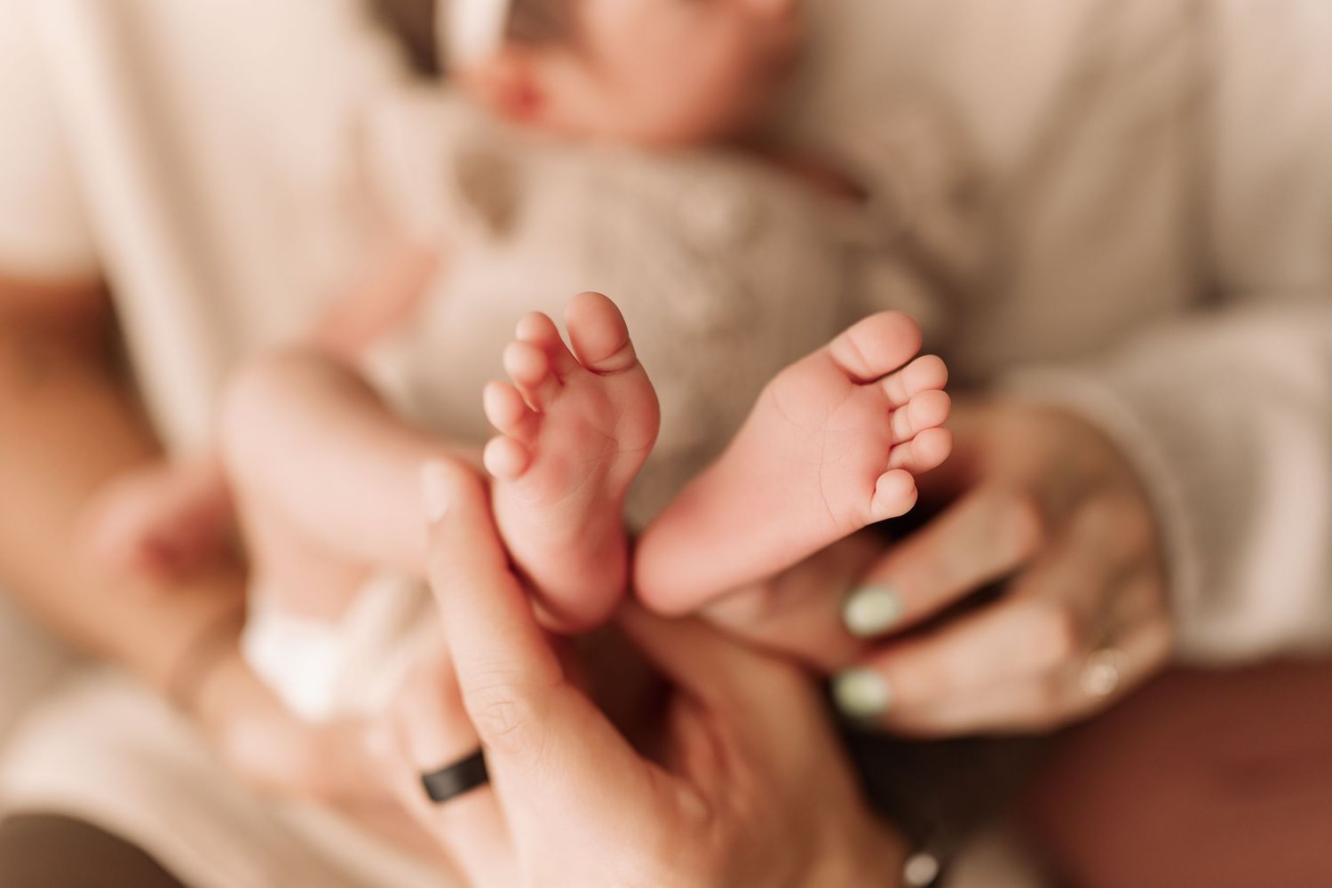 Close-up of tiny newborn baby feet being gently held by parents hands.