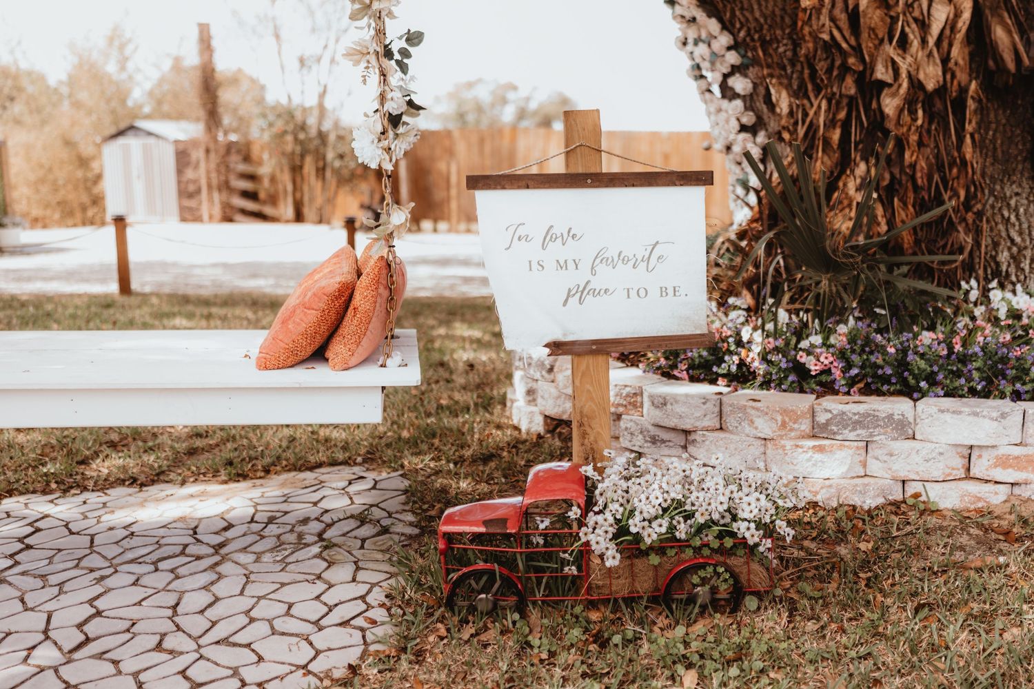 Rustic outdoor wedding ceremony setup with white benches and a sign reading this place is my favorite place to be.
