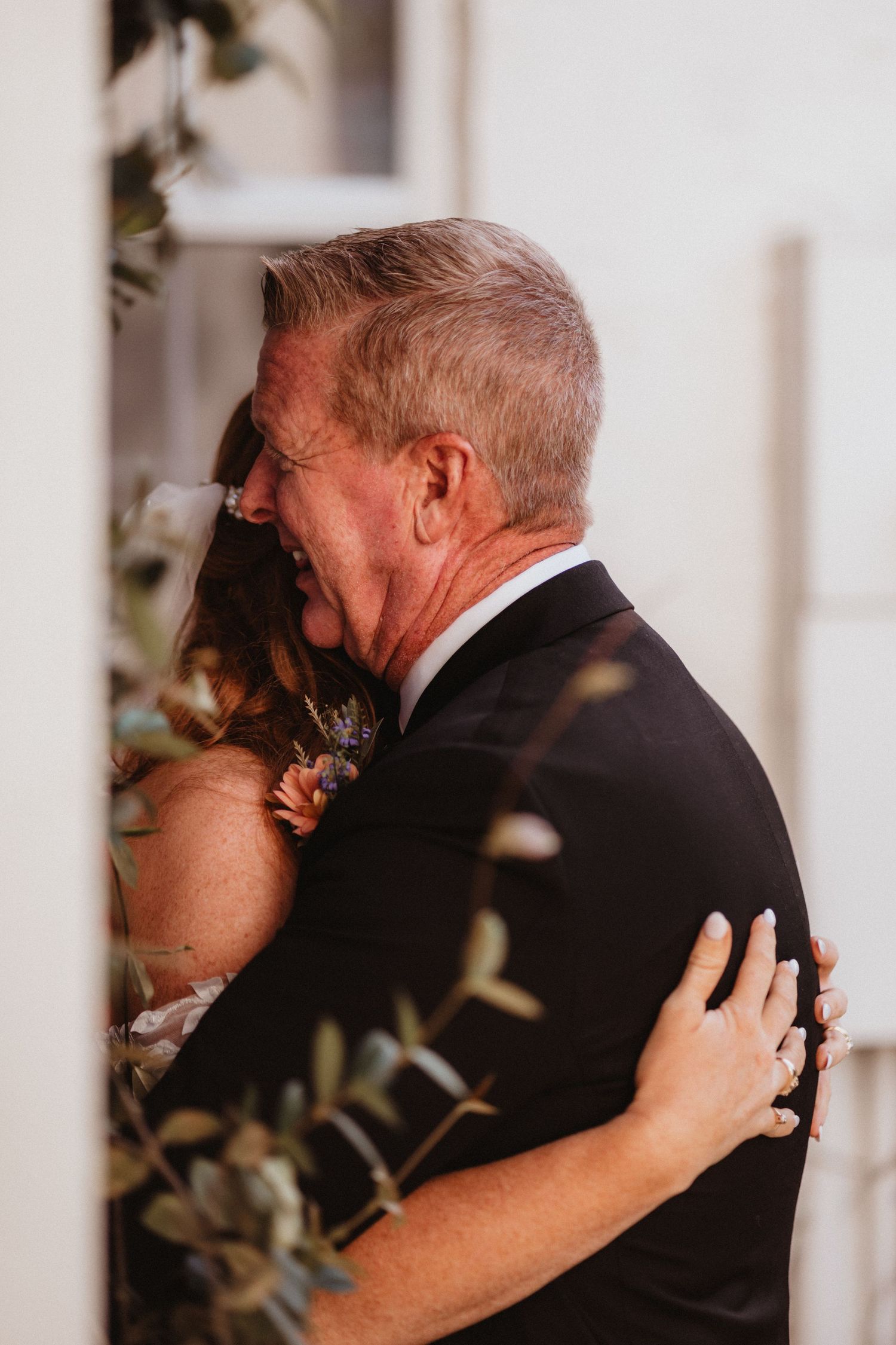 Emotional father of the bride shares a tearful first look hug with his daughter on wedding day.